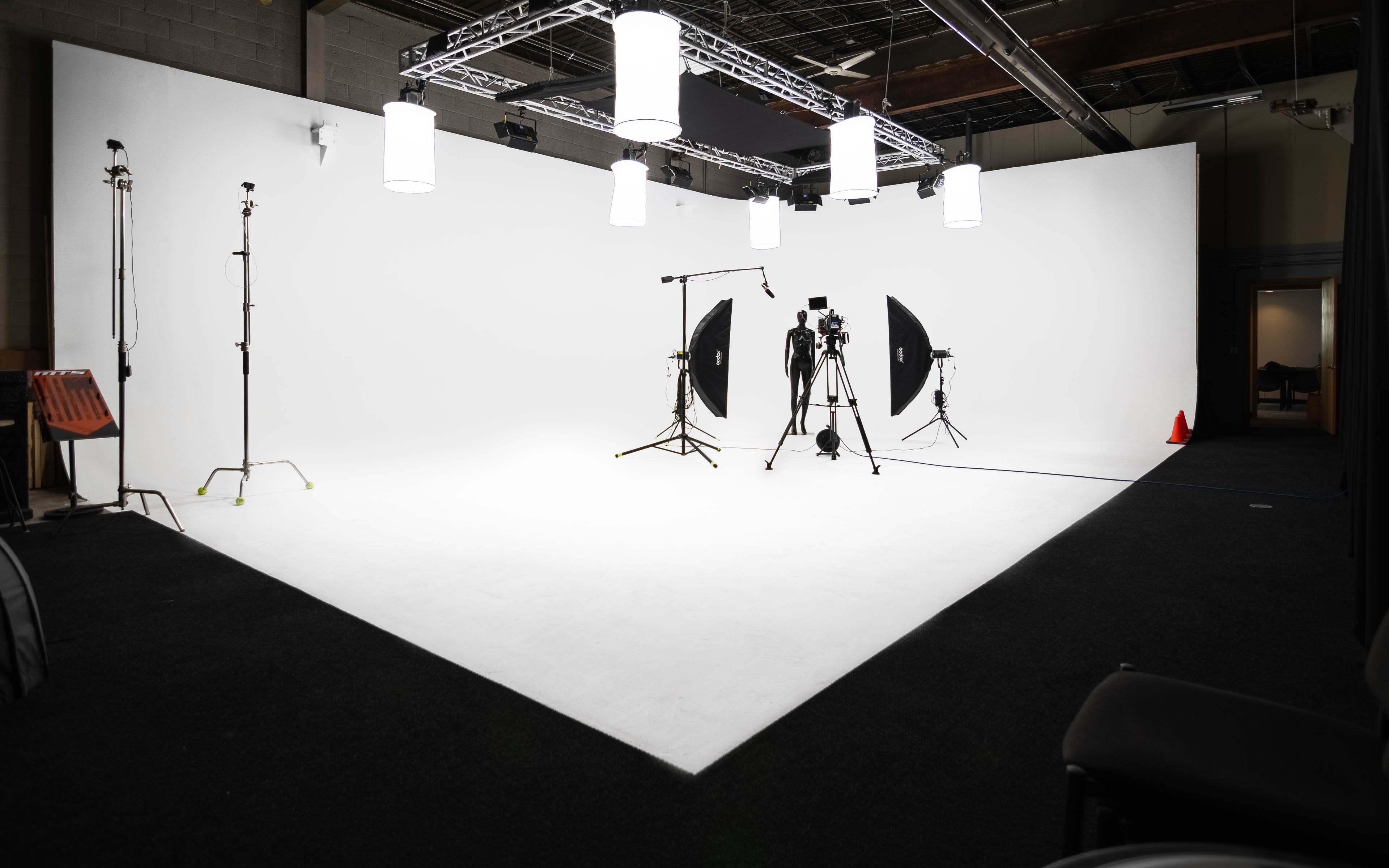 The image shows a photography studio set up with multiple lighting equipment, backdrops, and a camera positioned on a tripod.