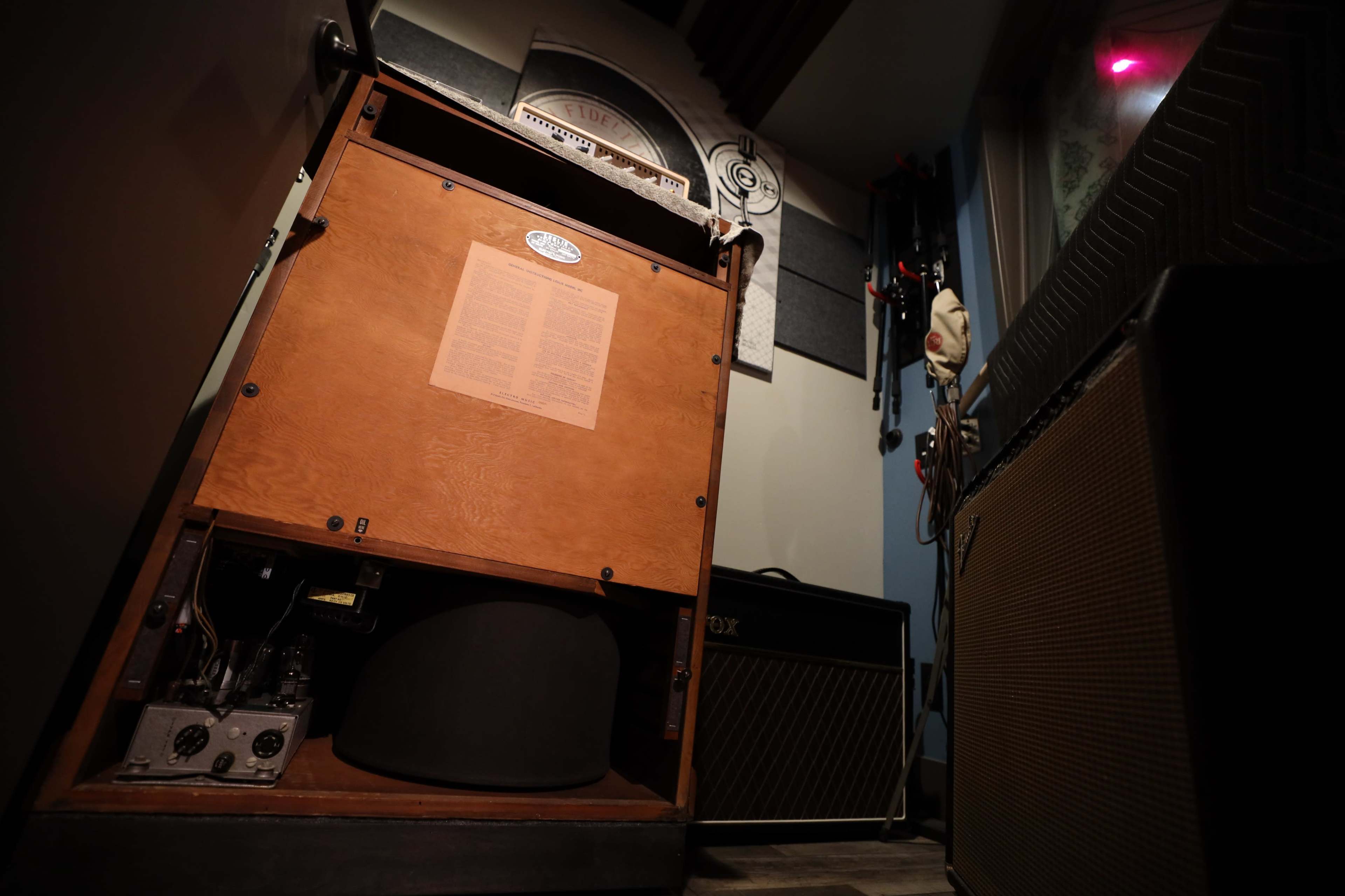 An interior music studio with an upright speaker cabinet and a guitar amplifier positioned against the walls.
