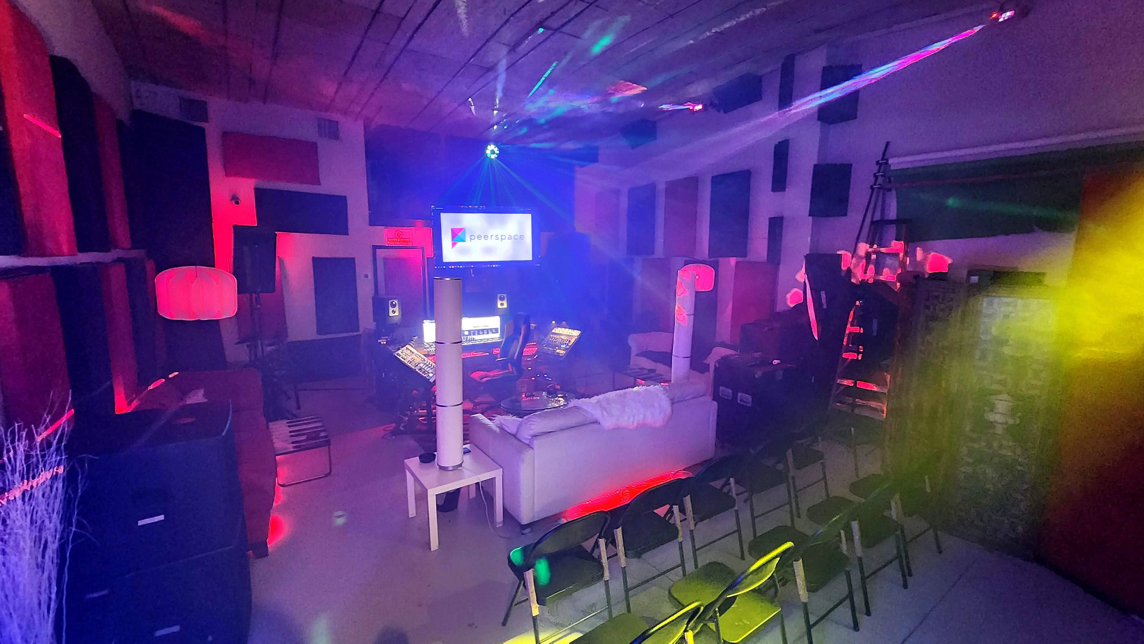 A music studio with various musical equipment, seating arranged in rows, and colorful lights illuminating the space.