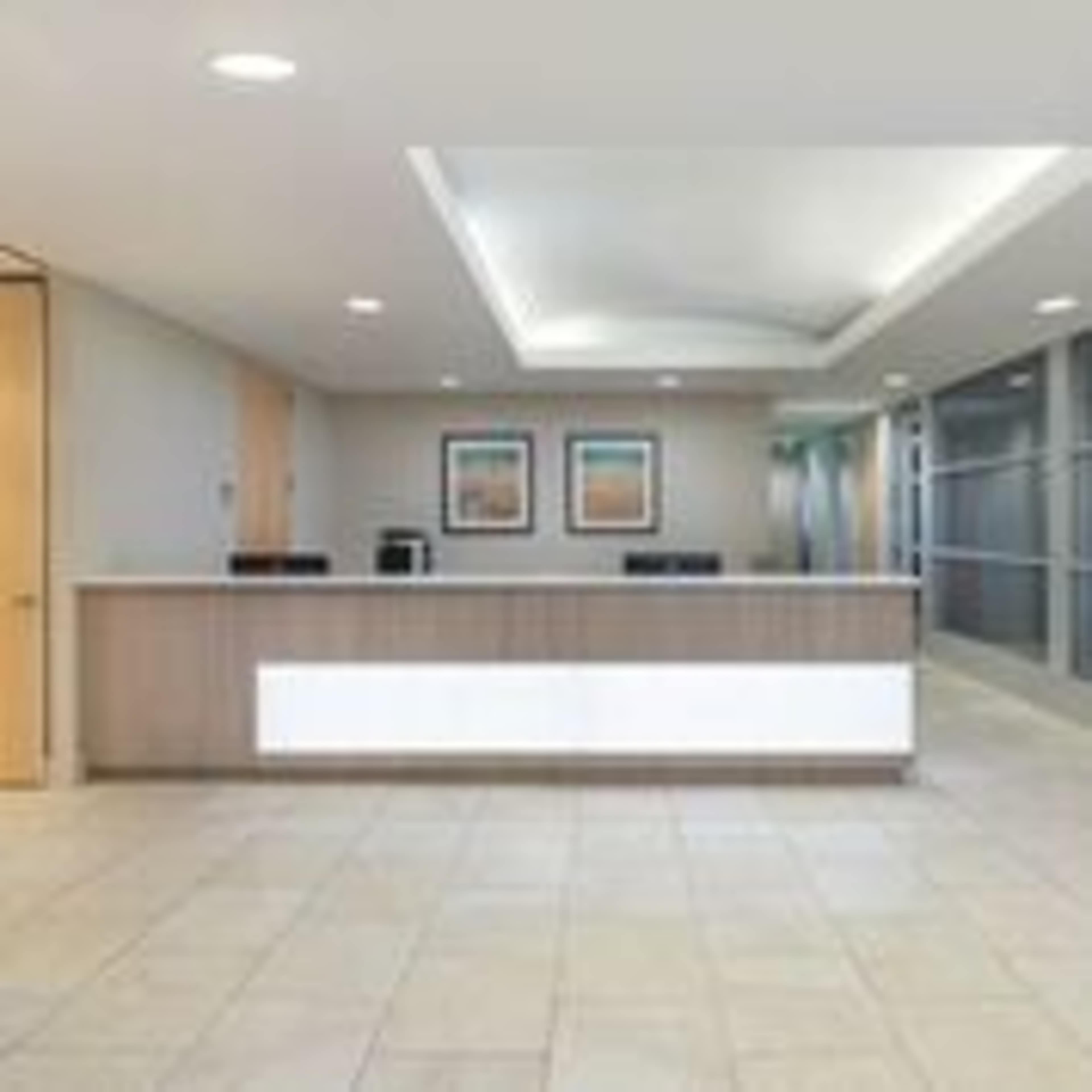 A modern reception area with a front desk, beige walls, and framed artwork.