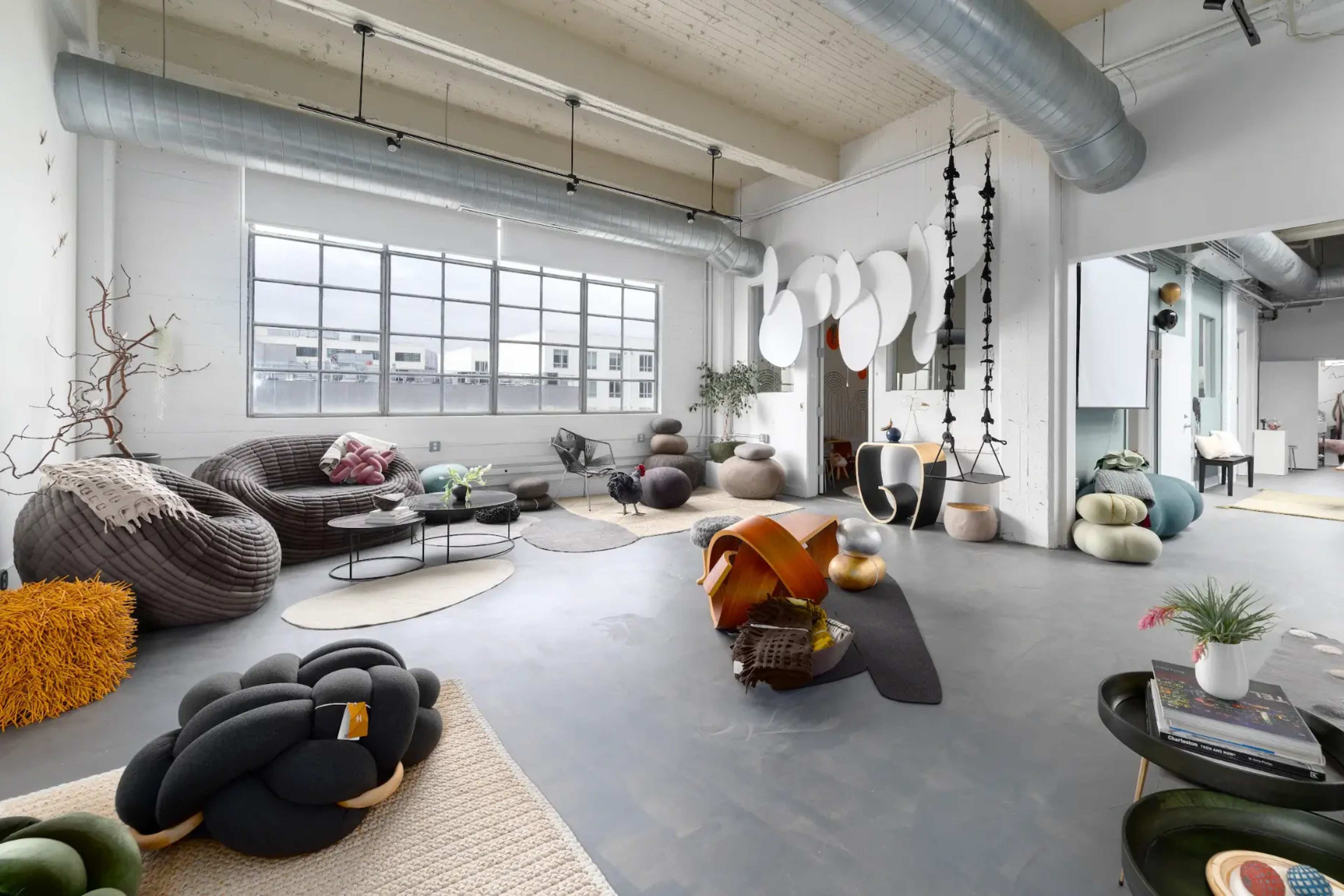 A spacious, modern living area featuring unique, textured furniture pieces and large windows allowing natural light to fill the room.
