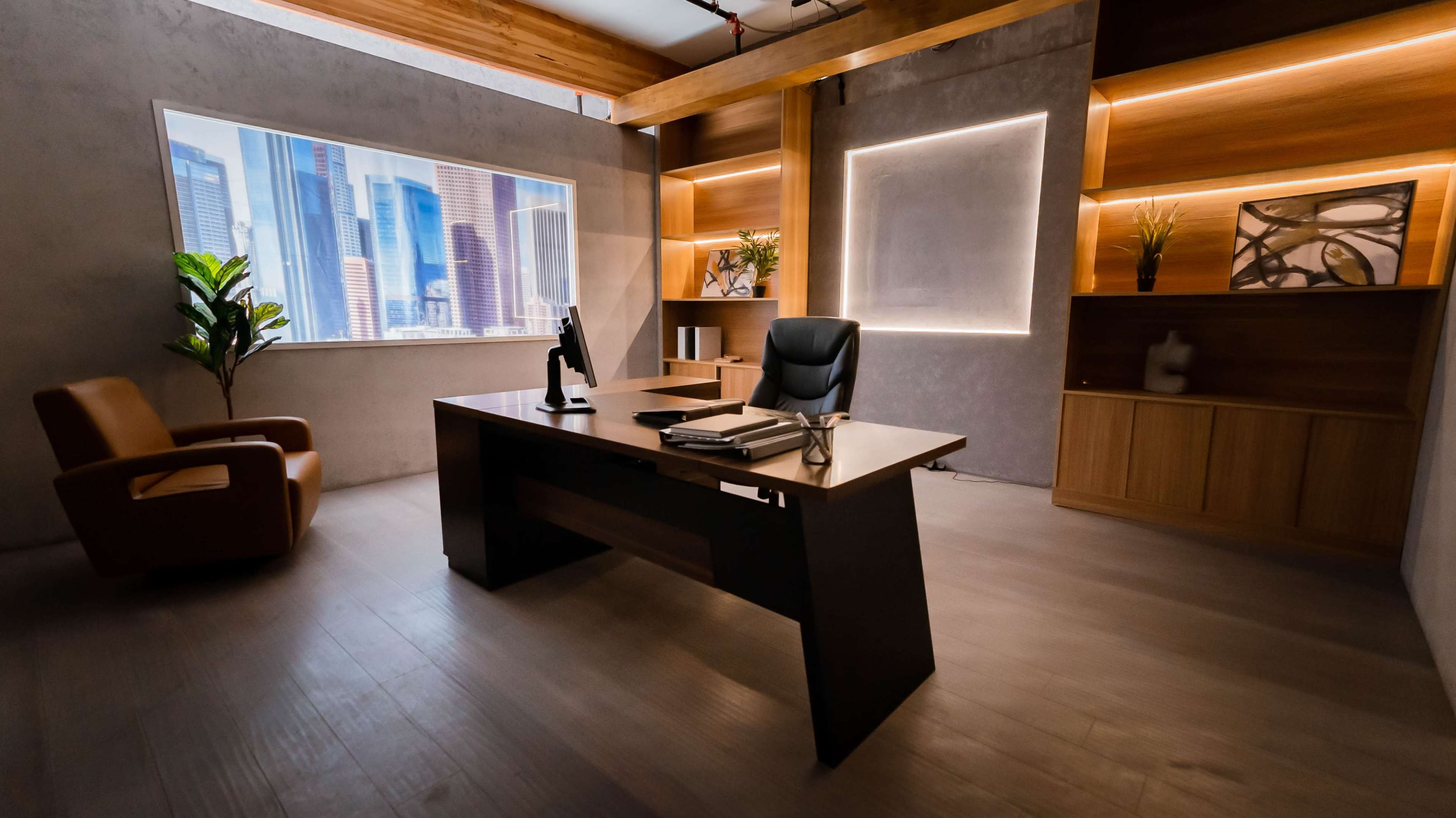 The image shows a modern office with a desk, an office chair, a contemporary armchair, and large windows displaying a city skyline.
