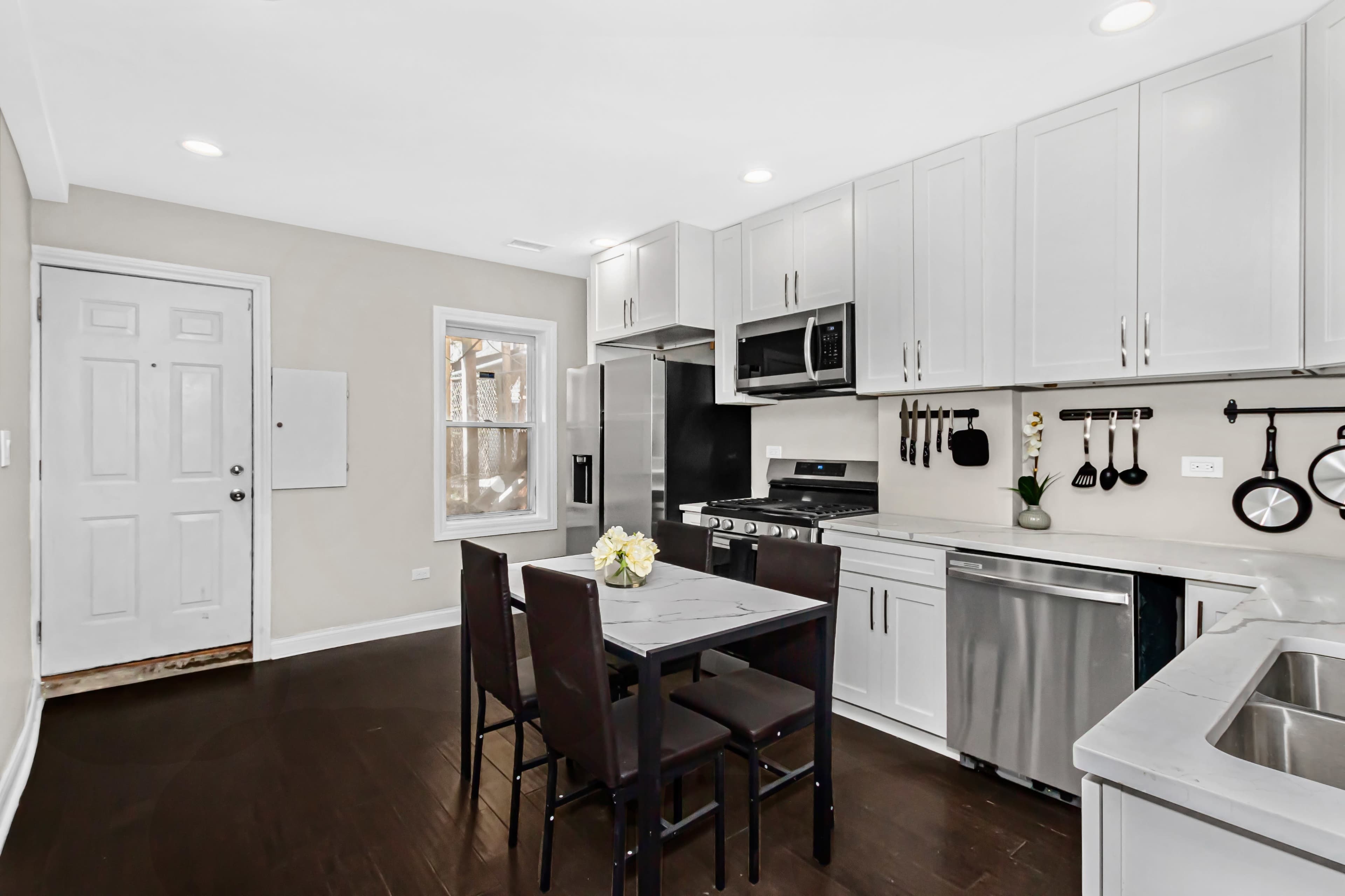 A modern kitchen featuring a small dining table with chairs, stainless steel appliances, and light gray cabinetry.
