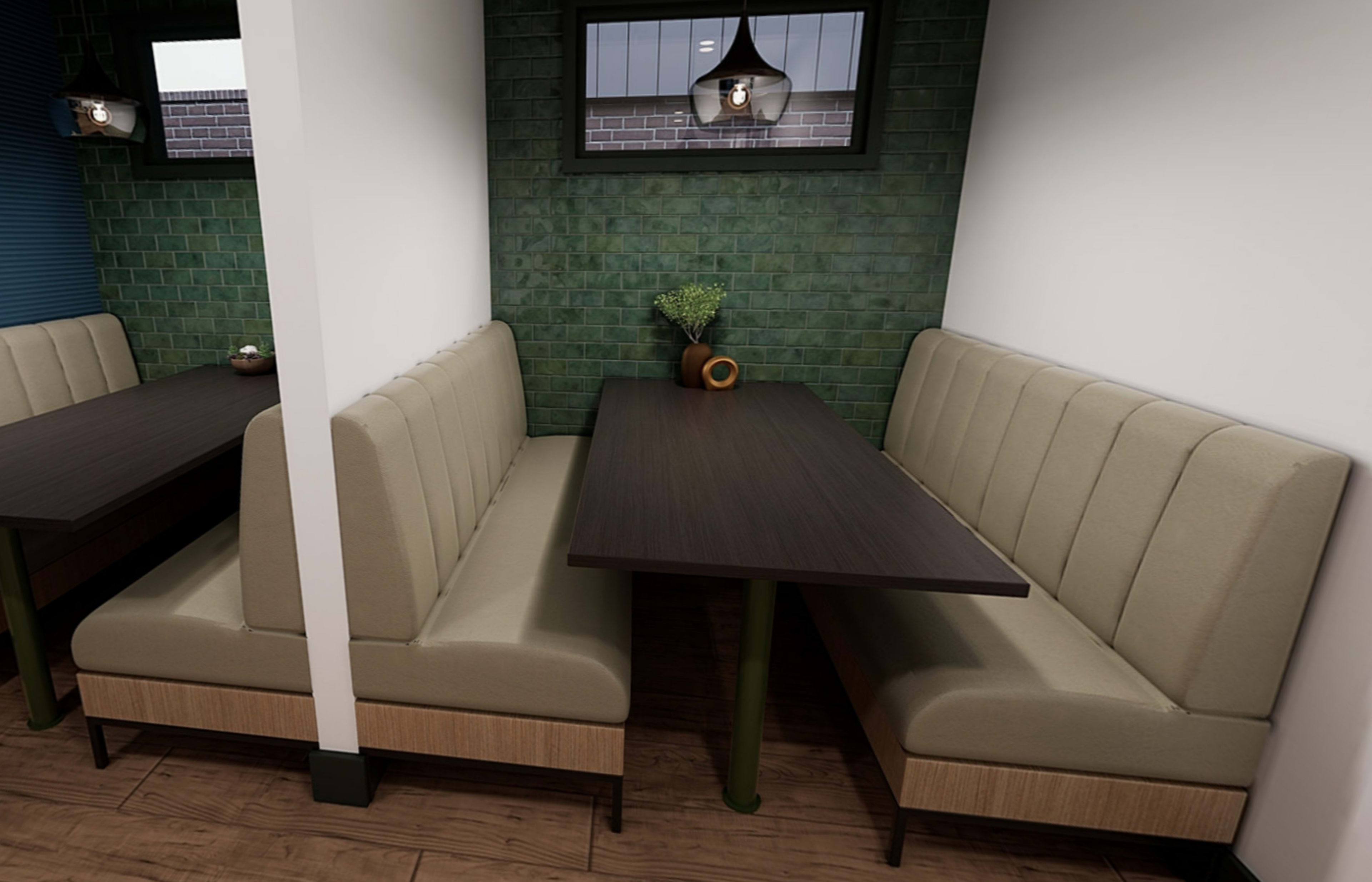 A modern dining area with two upholstered booths and a dark wooden table against a green tiled wall.