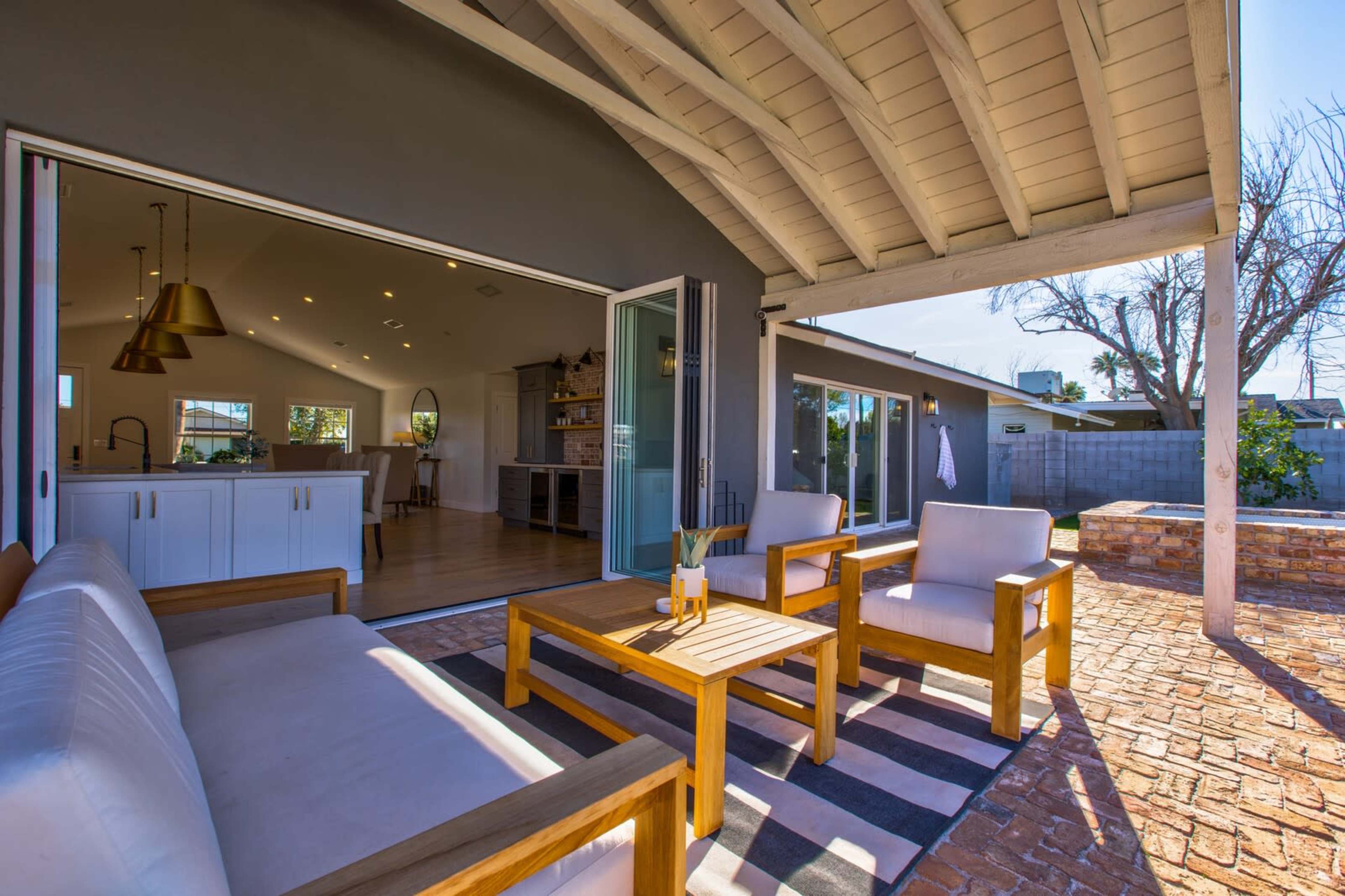 A modern outdoor seating area with wooden furniture and an open view of a sunlit interior space.