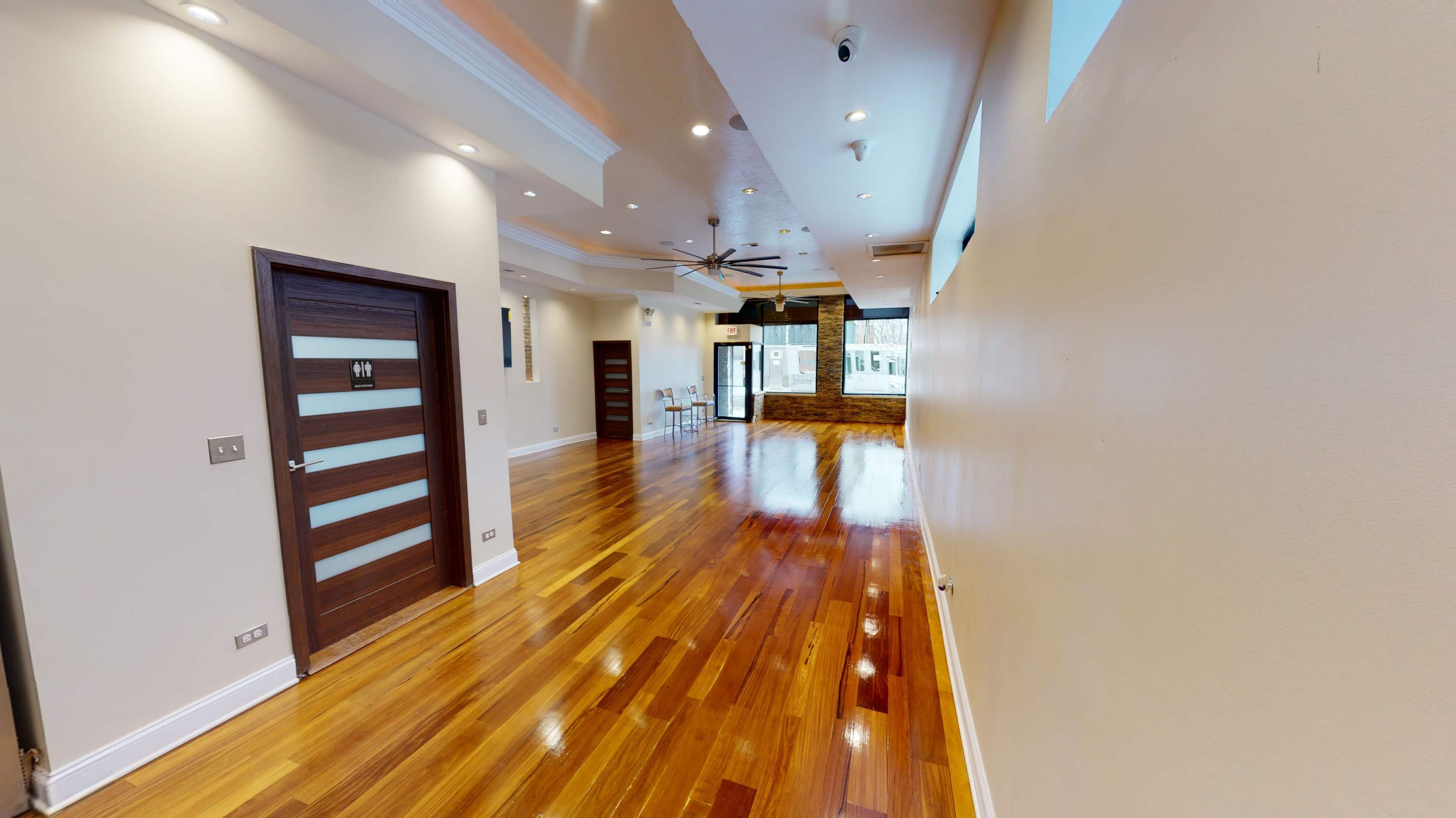 A spacious interior hallway with polished wooden floors, modern lighting, and a series of doors leading into other rooms.
