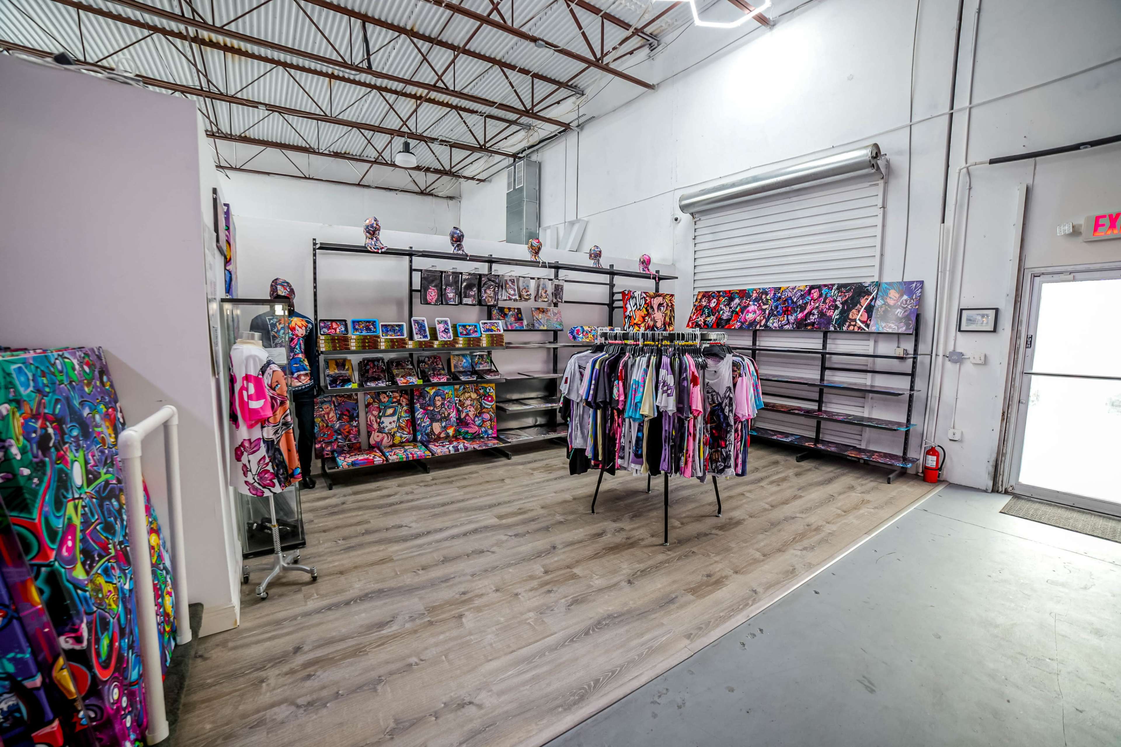 A colorful merchandise display area with clothing racks and walls adorned with vibrant artwork inside a spacious retail shop.