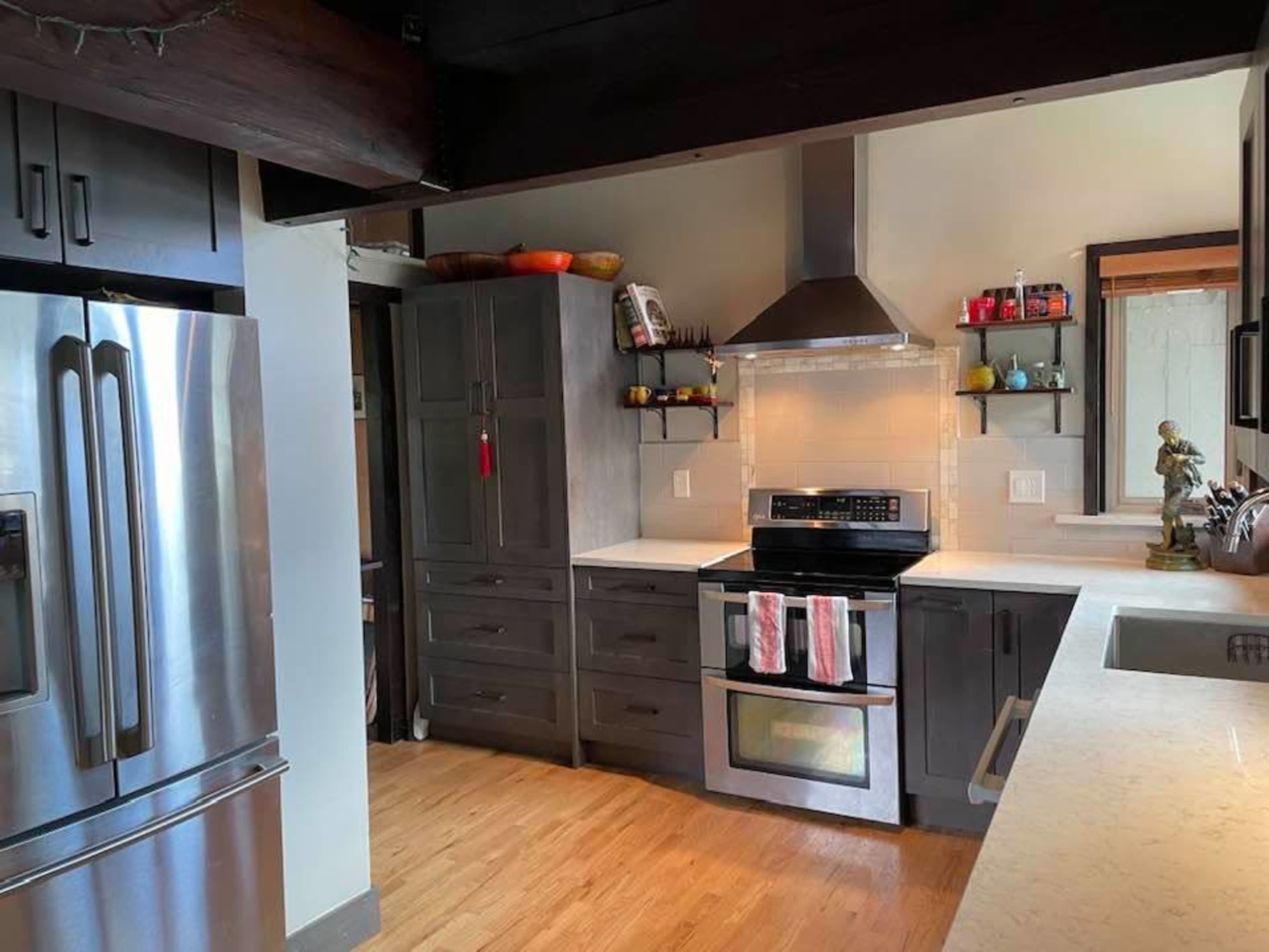 A modern kitchen featuring gray cabinetry, stainless steel appliances, and a white countertop.