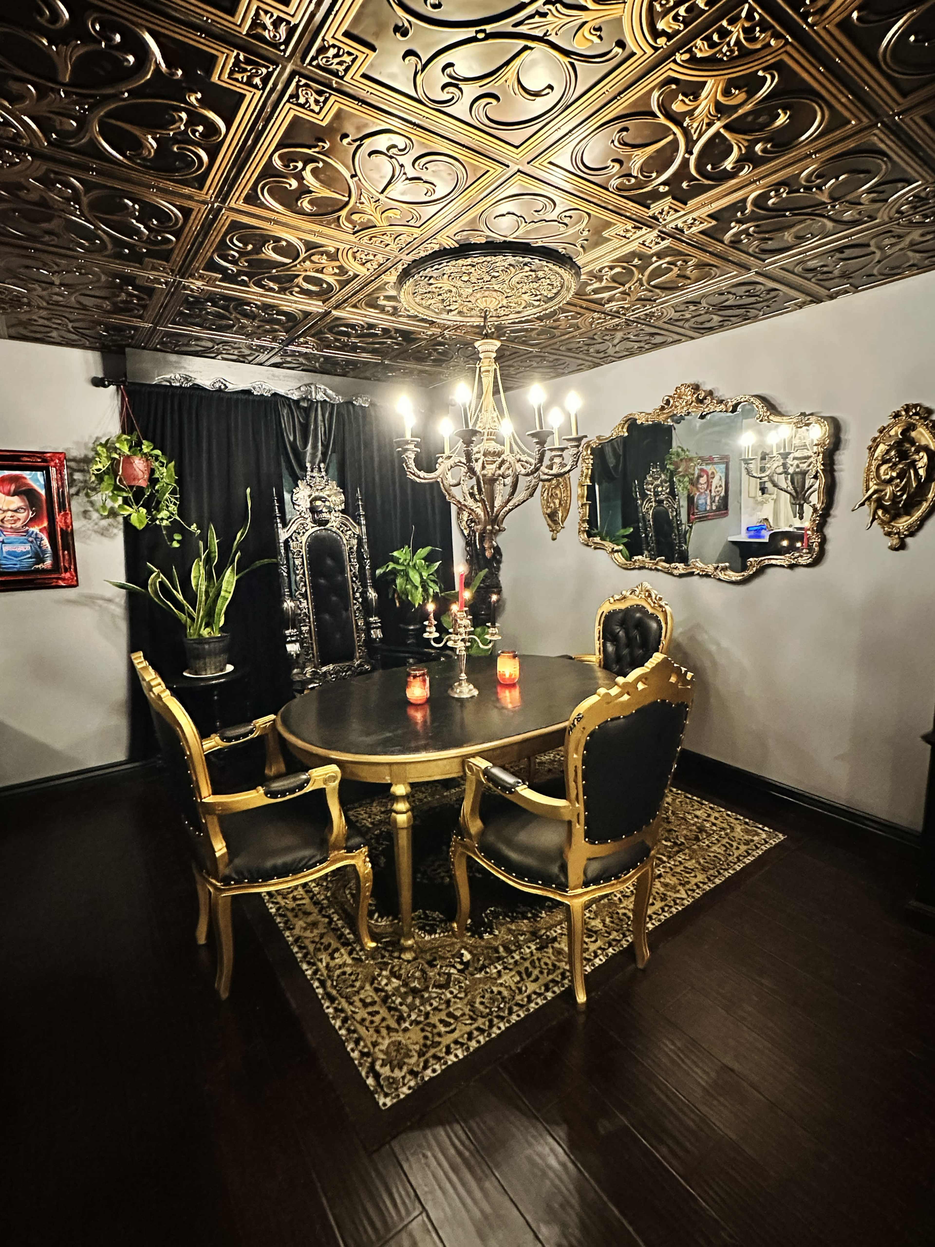 The image shows a lavish dining room featuring a round table surrounded by four ornate chairs, a chandelier, and decorative mirrors on the walls.