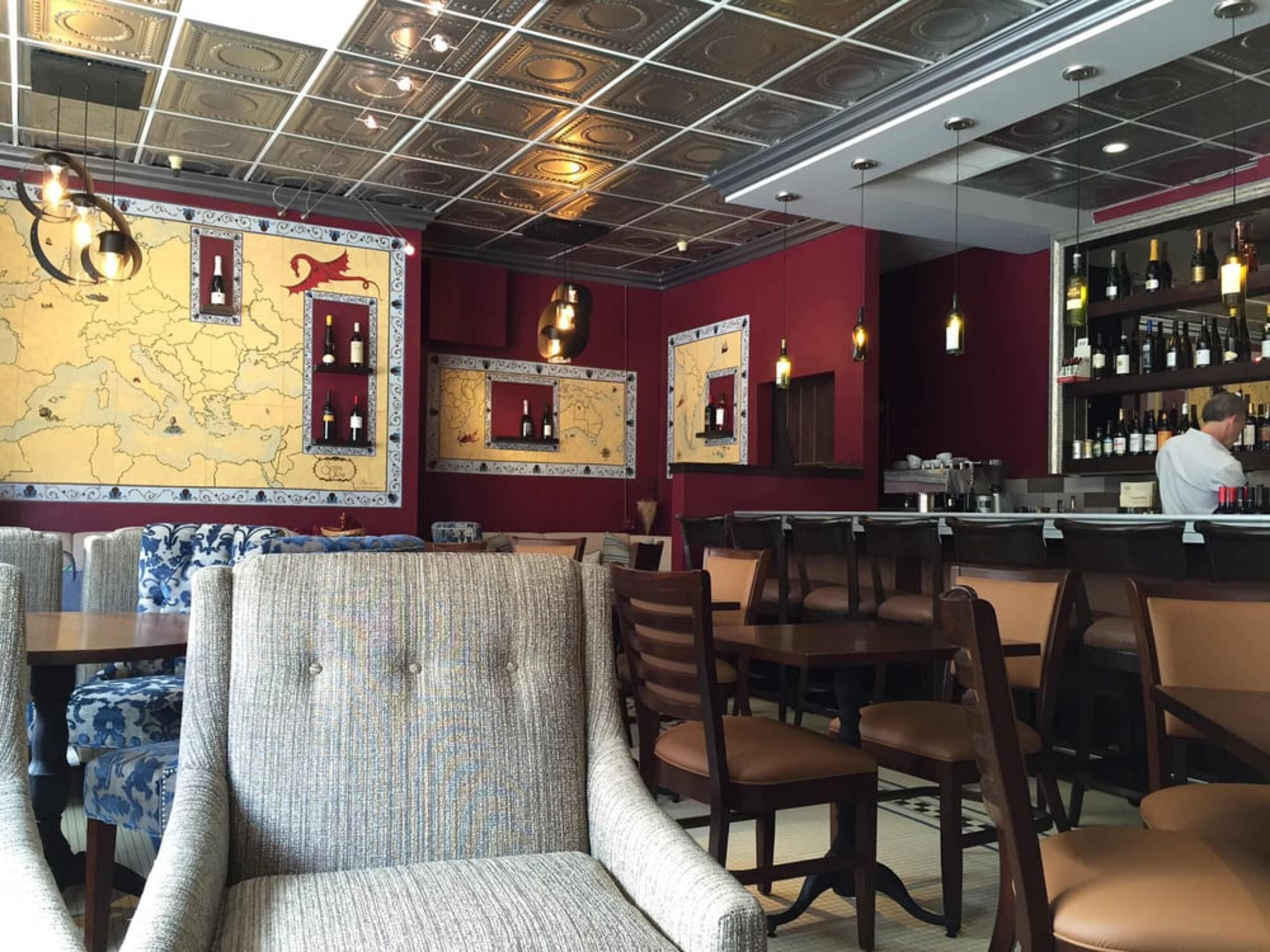 A restaurant interior featuring map-themed wall decor, wooden furniture, and soft lighting.
