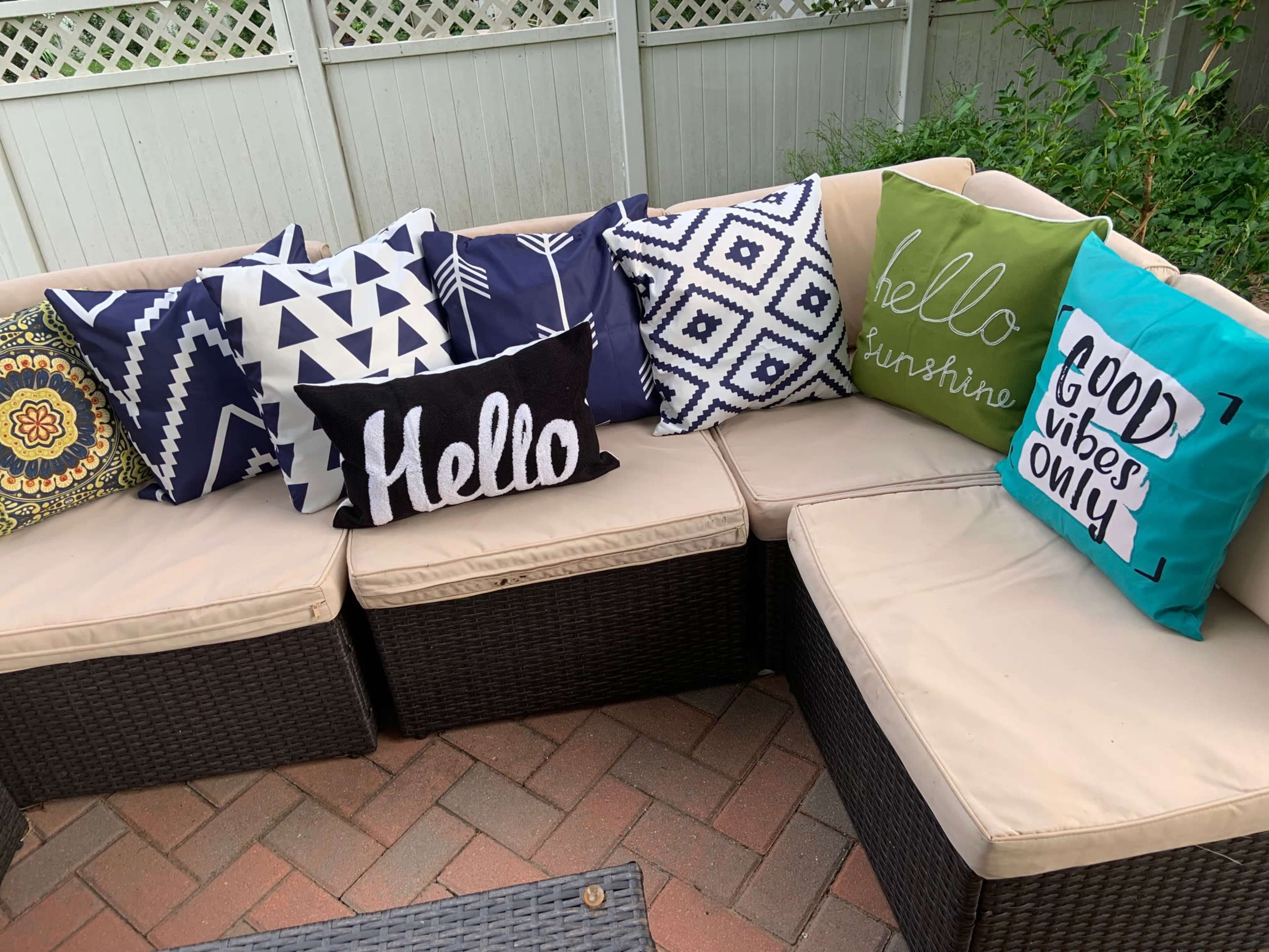 A sectional outdoor couch with various patterned and colored decorative pillows arranged on it.
