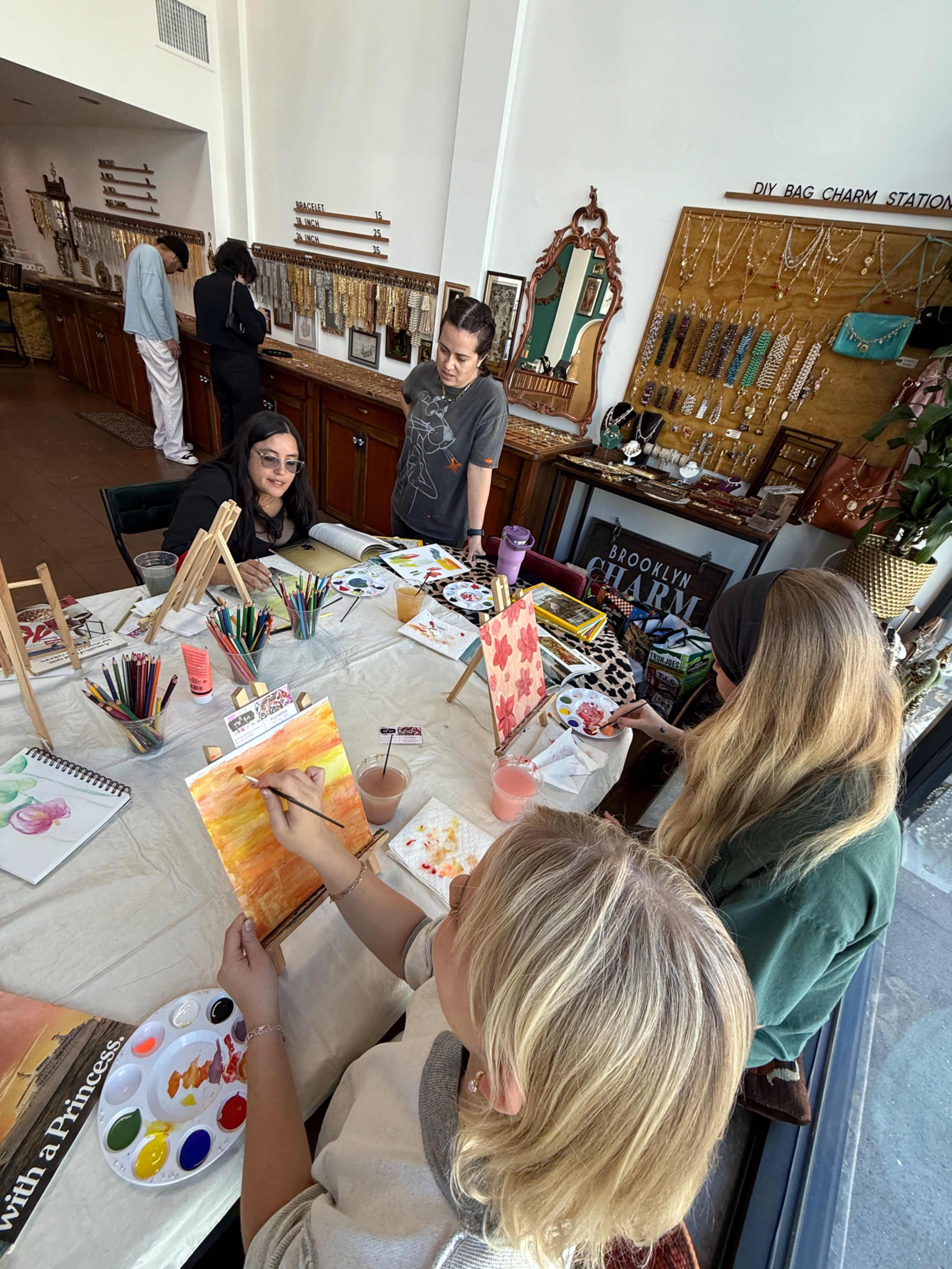 A group of four people is engaged in a painting activity at a table adorned with art supplies in a creative studio.