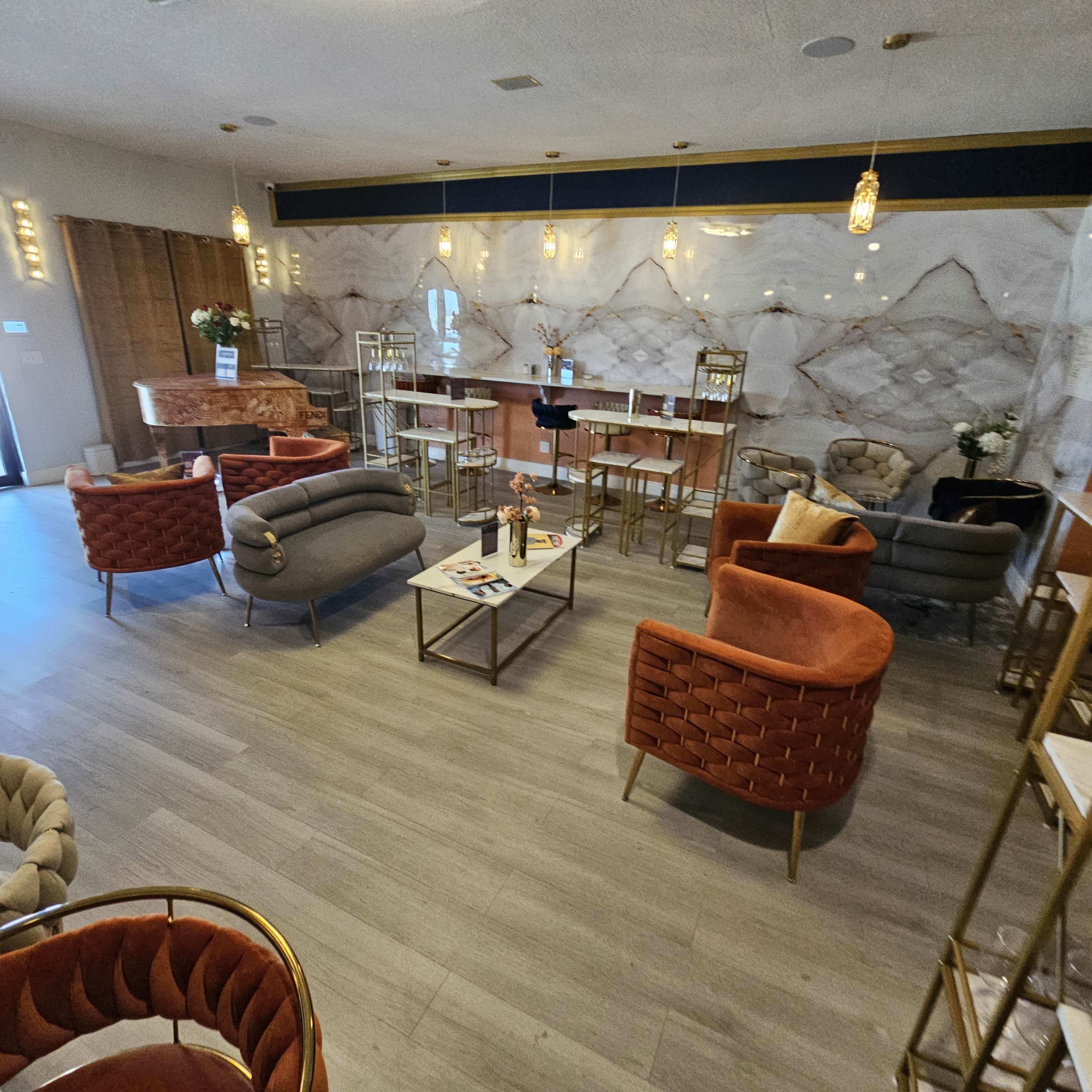 The image shows a modern lounge area featuring stylish seating arrangements with various armchairs and a coffee table, complemented by elegant lighting and decorative elements.