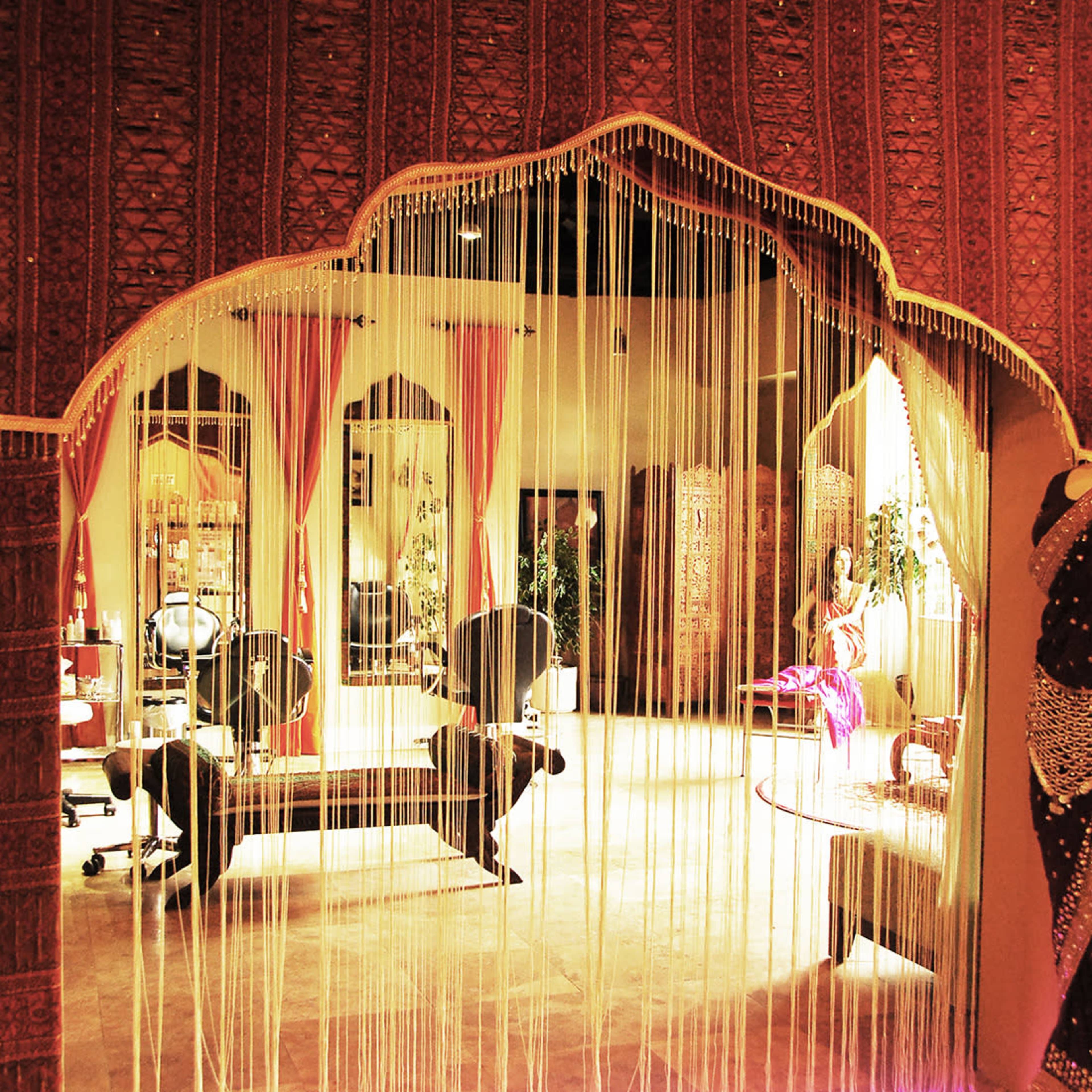 A spacious interior with an ornate archway draped in strings, leading into a decorative room adorned with mirrors and traditional furnishings.