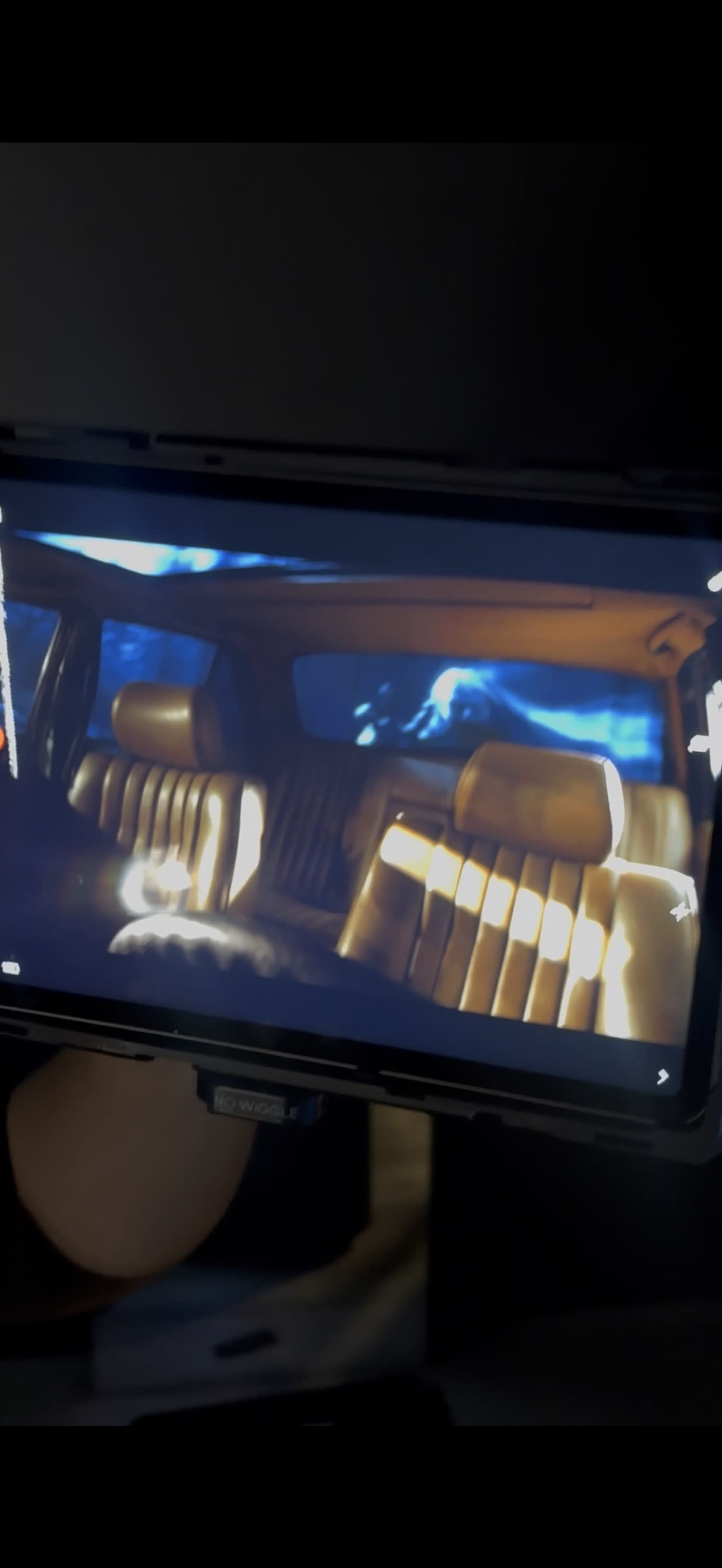 A person is holding a device displaying an image of a luxurious car interior with leather seats.
