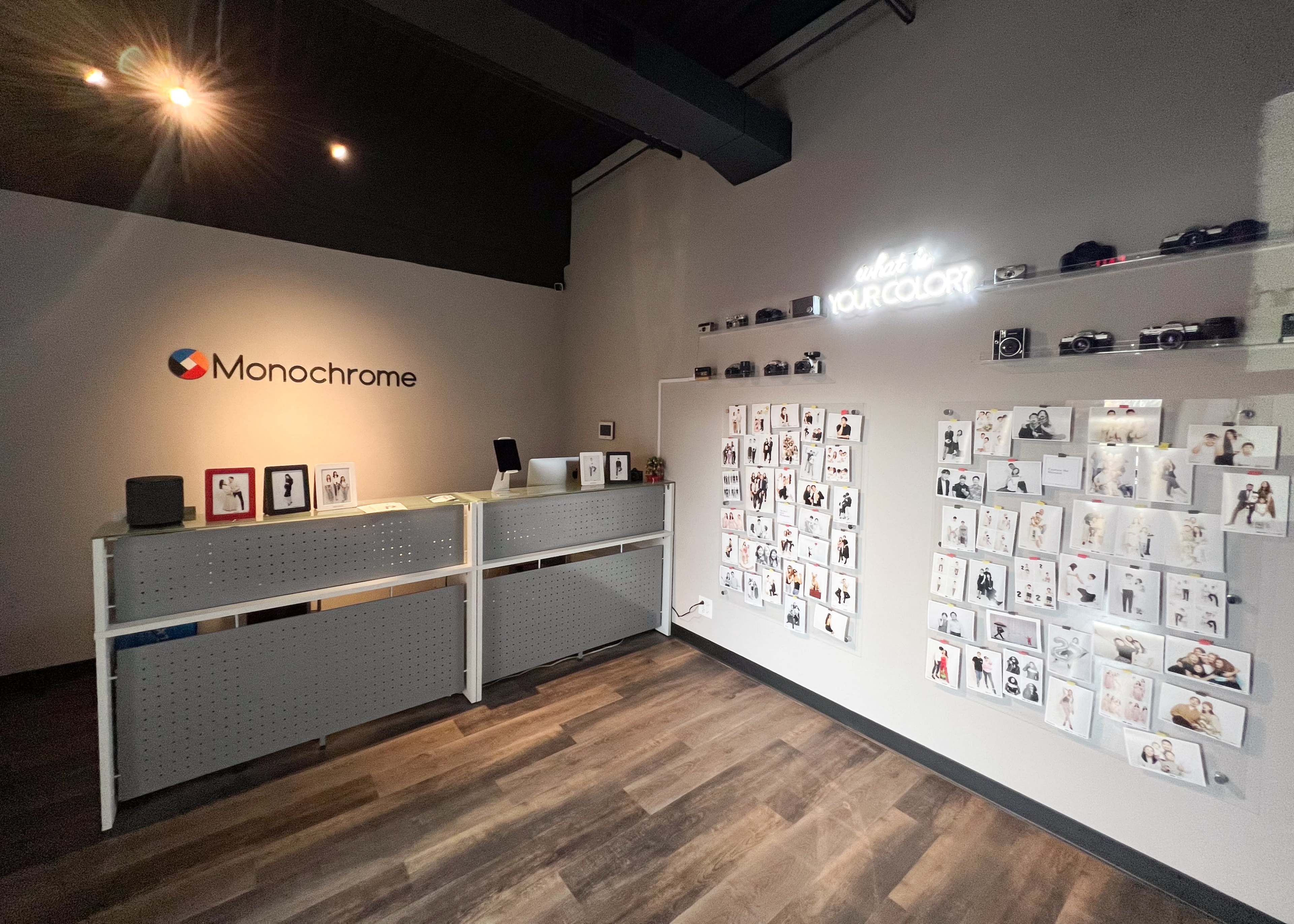 The image shows an interior space of a studio named "Monochrome," featuring a reception desk and a wall covered with photographs.