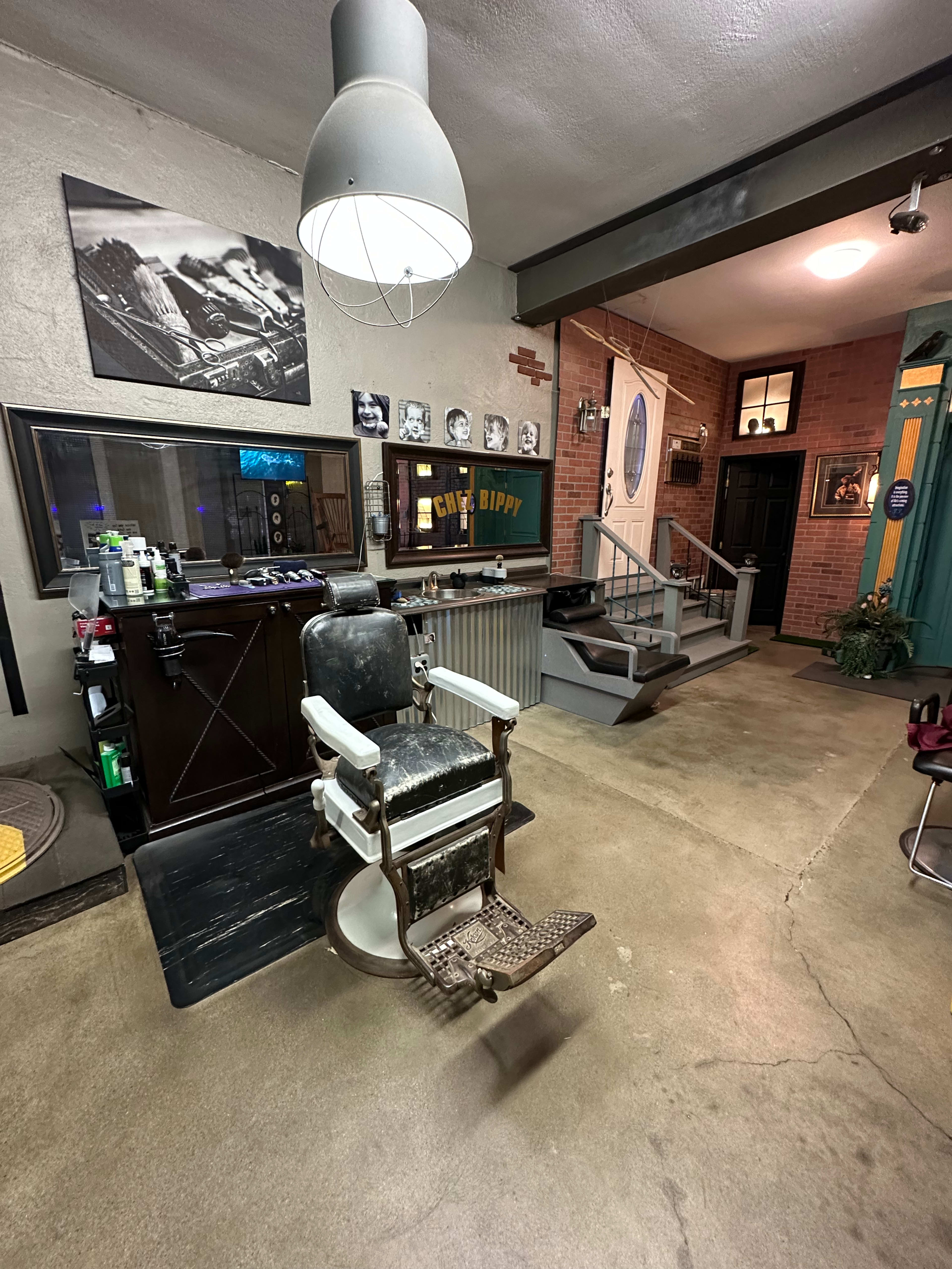 A vintage barber shop interior featuring a traditional barber chair, a large mirror, and retro décor elements like photographs and signage.