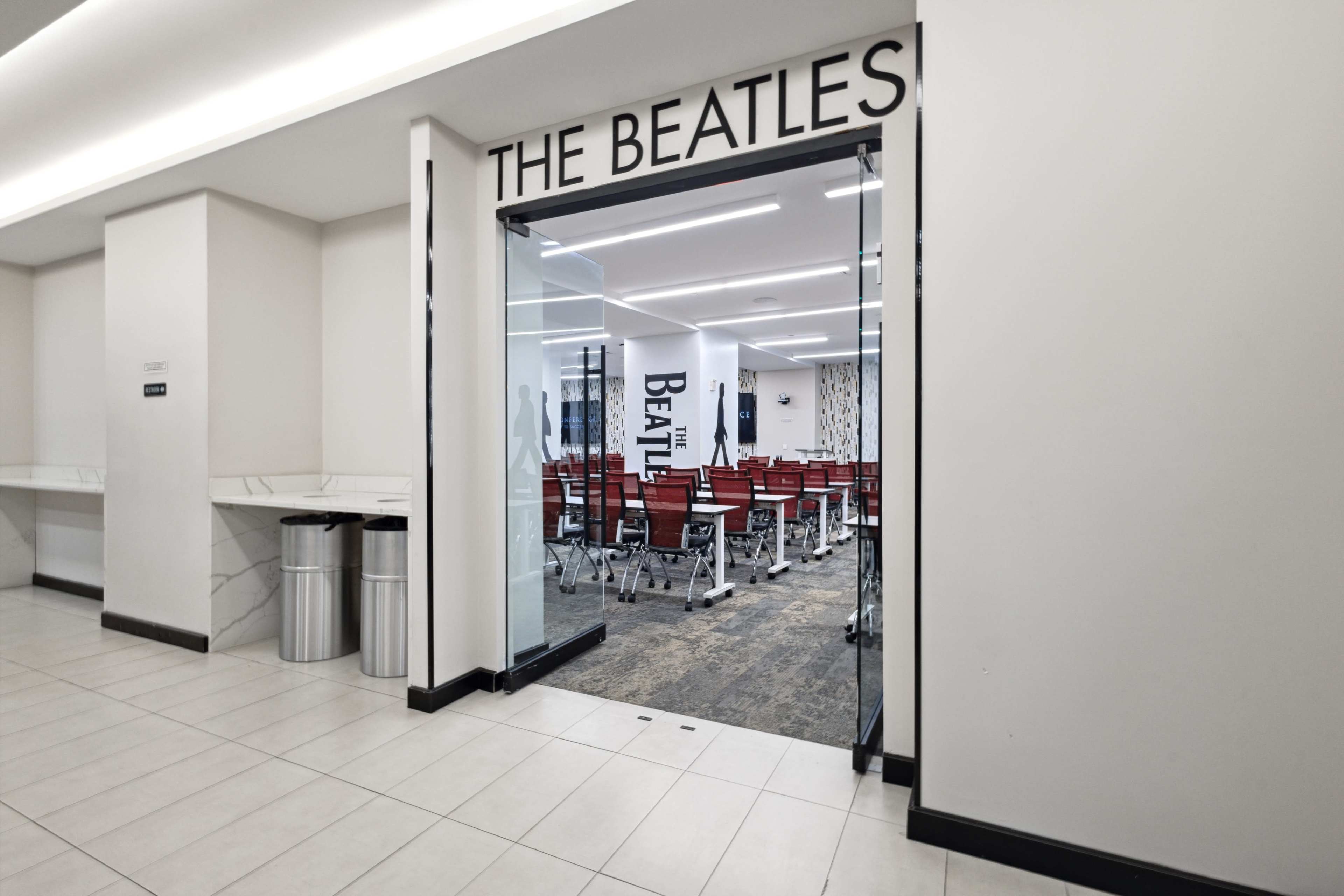 The entrance to a room labeled "THE BEATLES" is visible, featuring empty chairs arranged for a gathering.