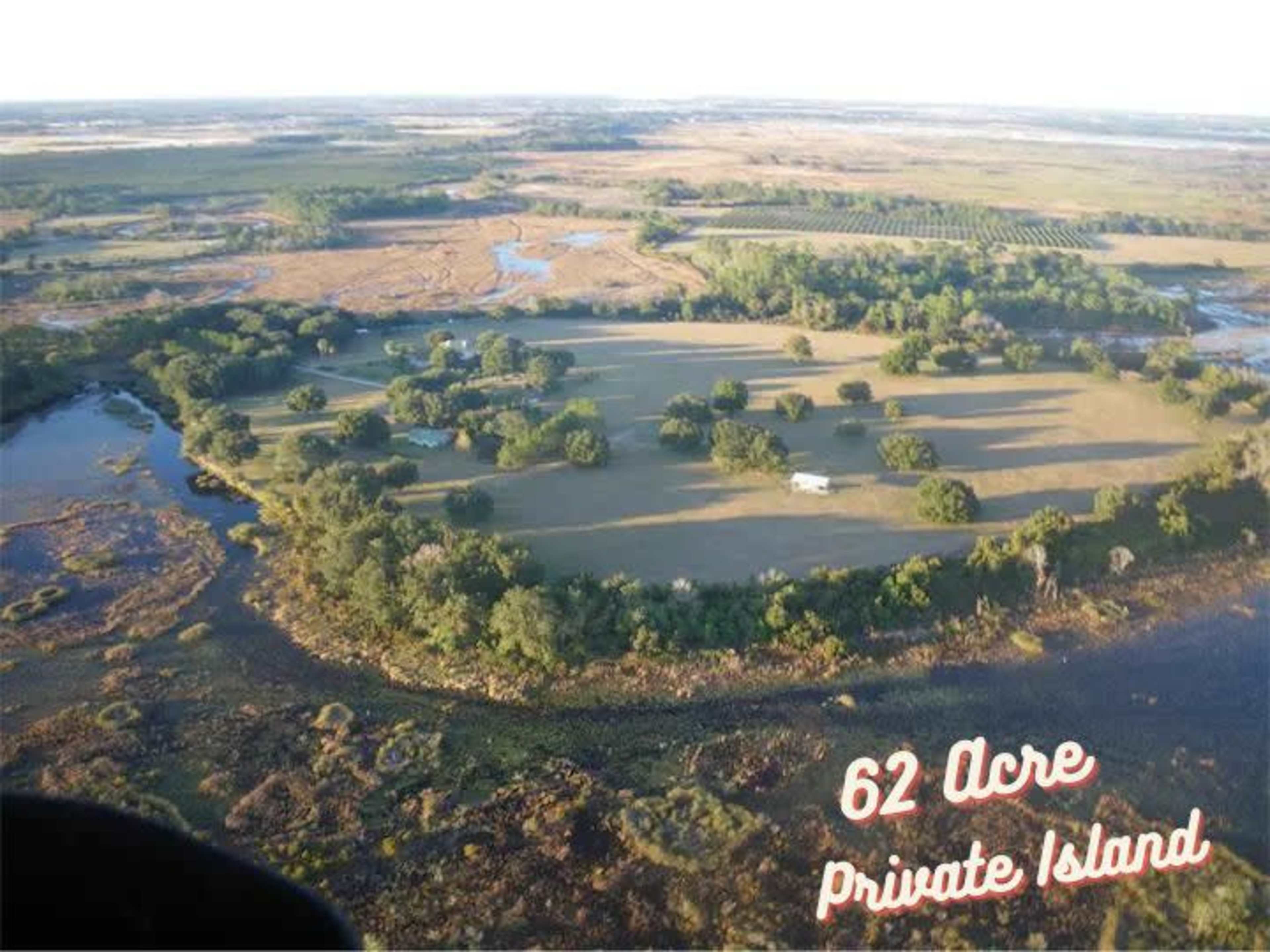 A 62-acre private island with green trees and open fields surrounded by water.