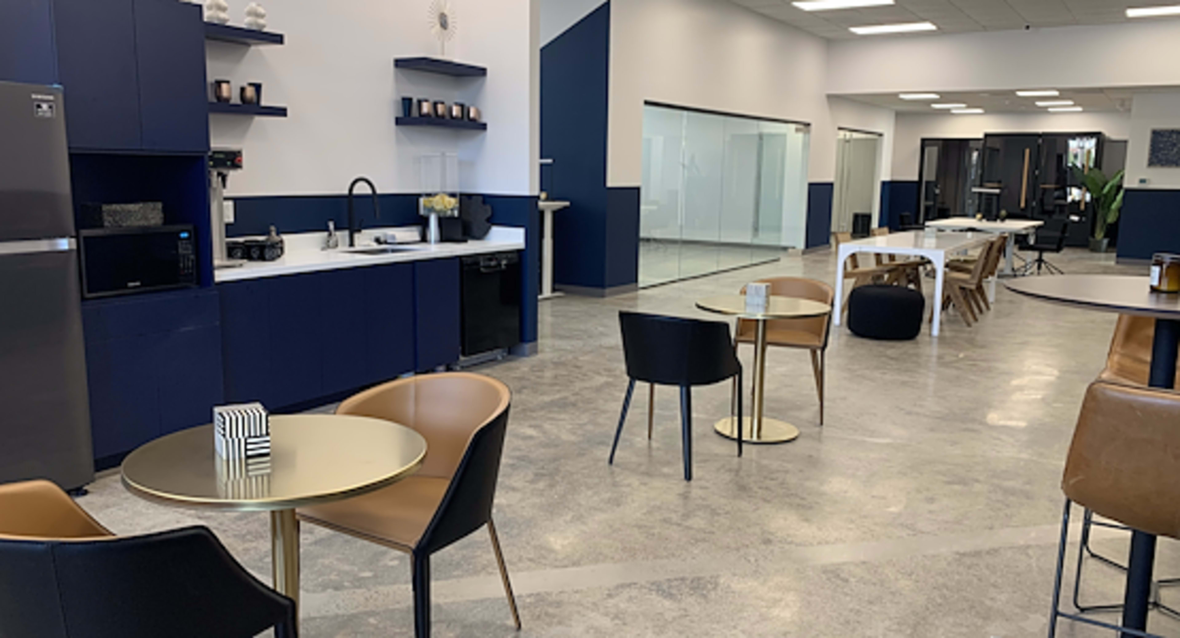 The image shows a modern kitchen and dining area with a sleek countertop, table seating, and appliances in an open, well-lit space.