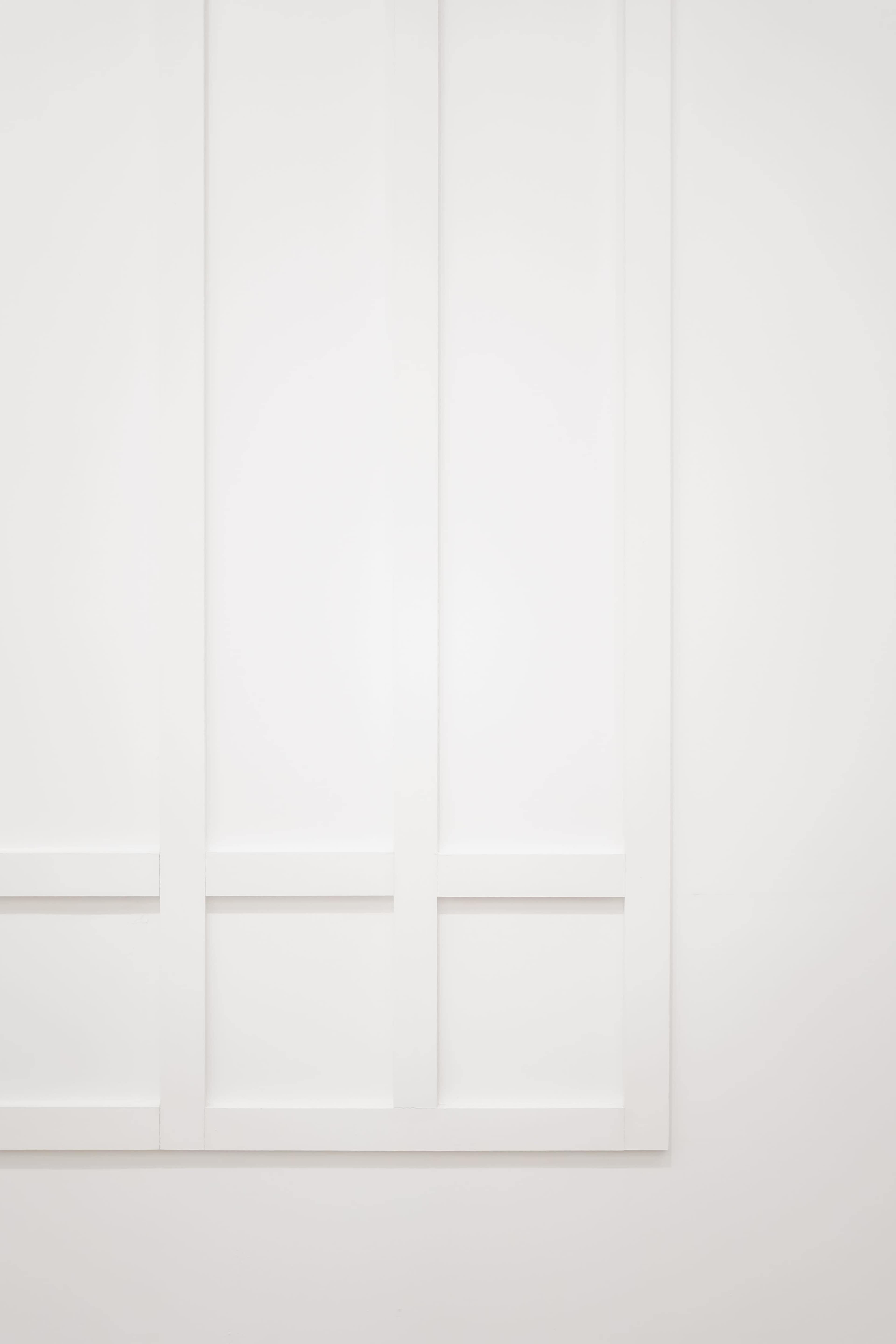 The image features a simple white wall with a grid pattern created by horizontal and vertical panels.