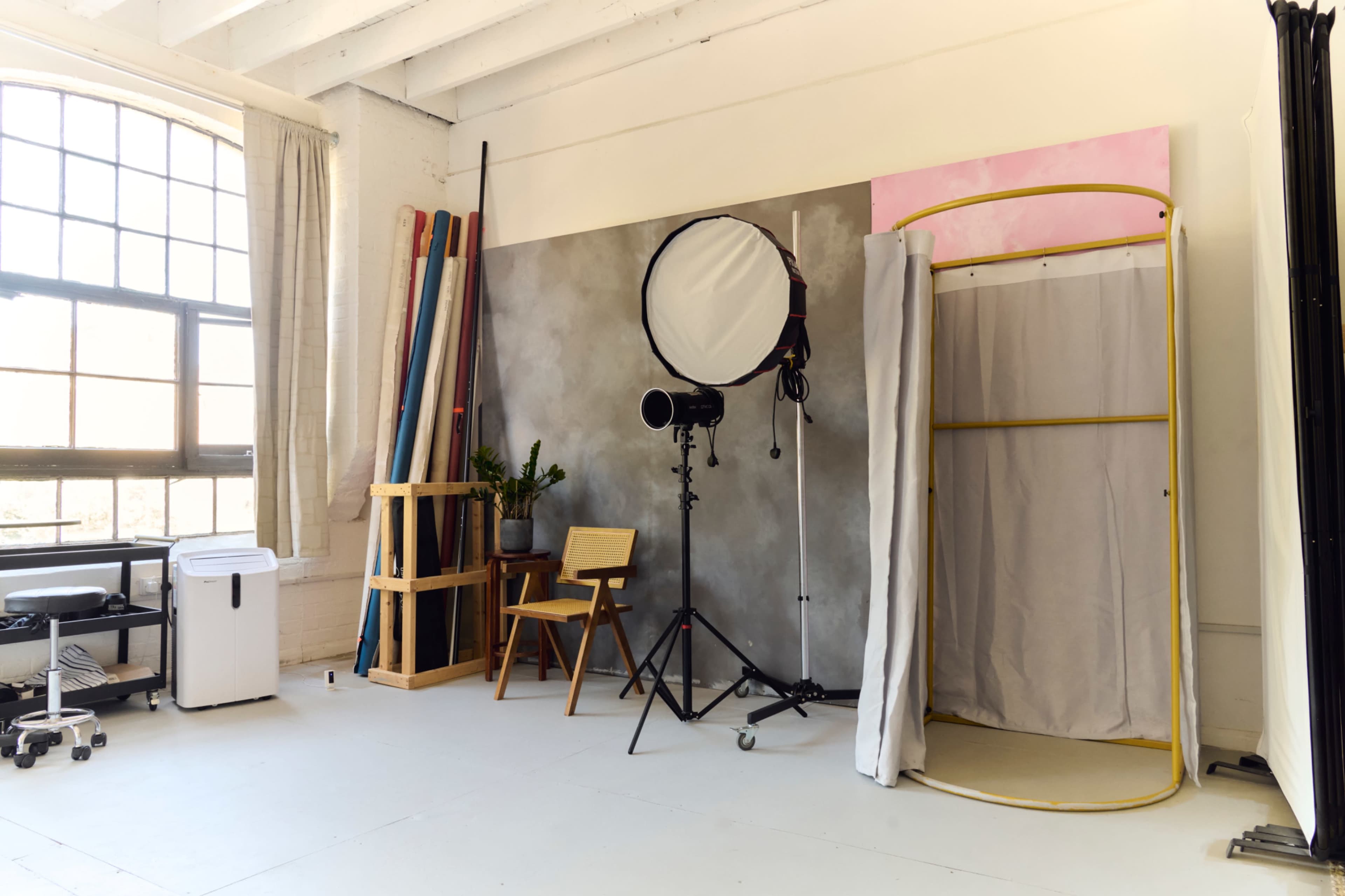 The image shows a photography studio featuring a backdrop, lighting equipment, and various props arranged systematically.