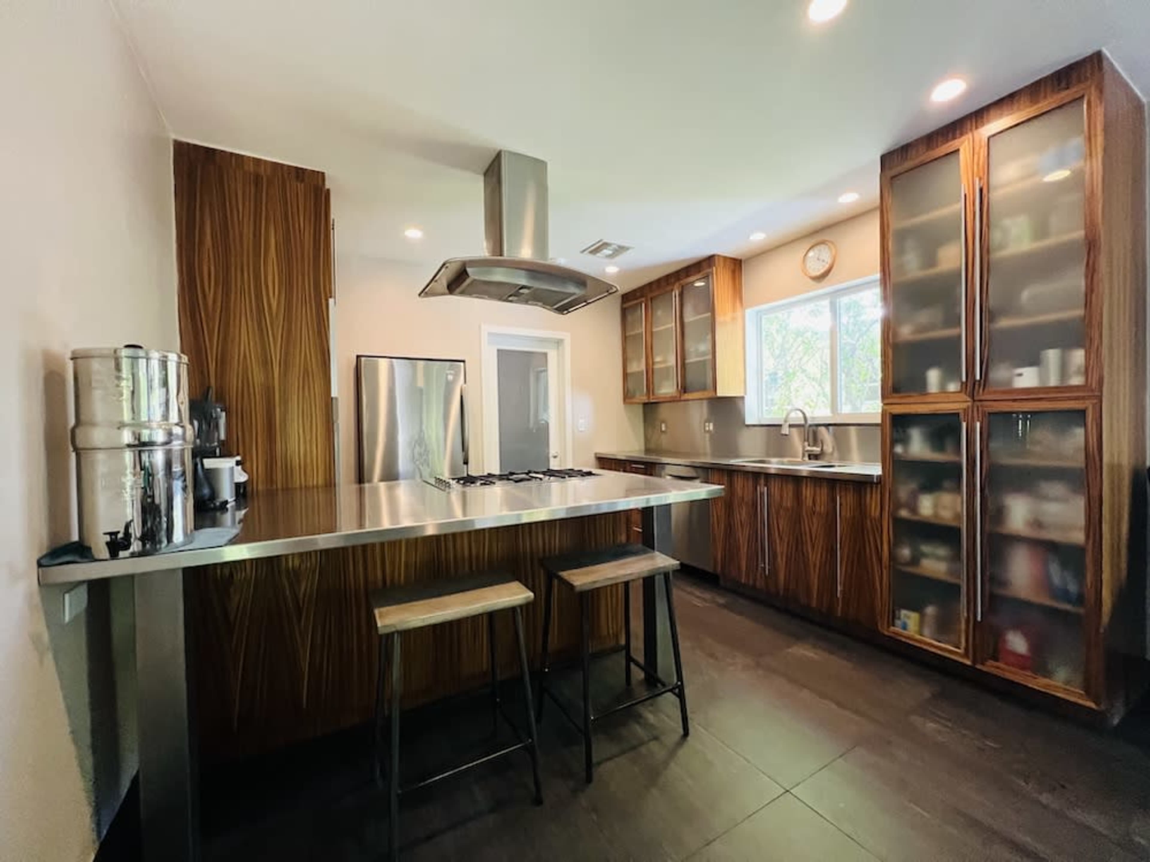 A modern kitchen with a central island, stainless steel appliances, and wooden cabinetry.