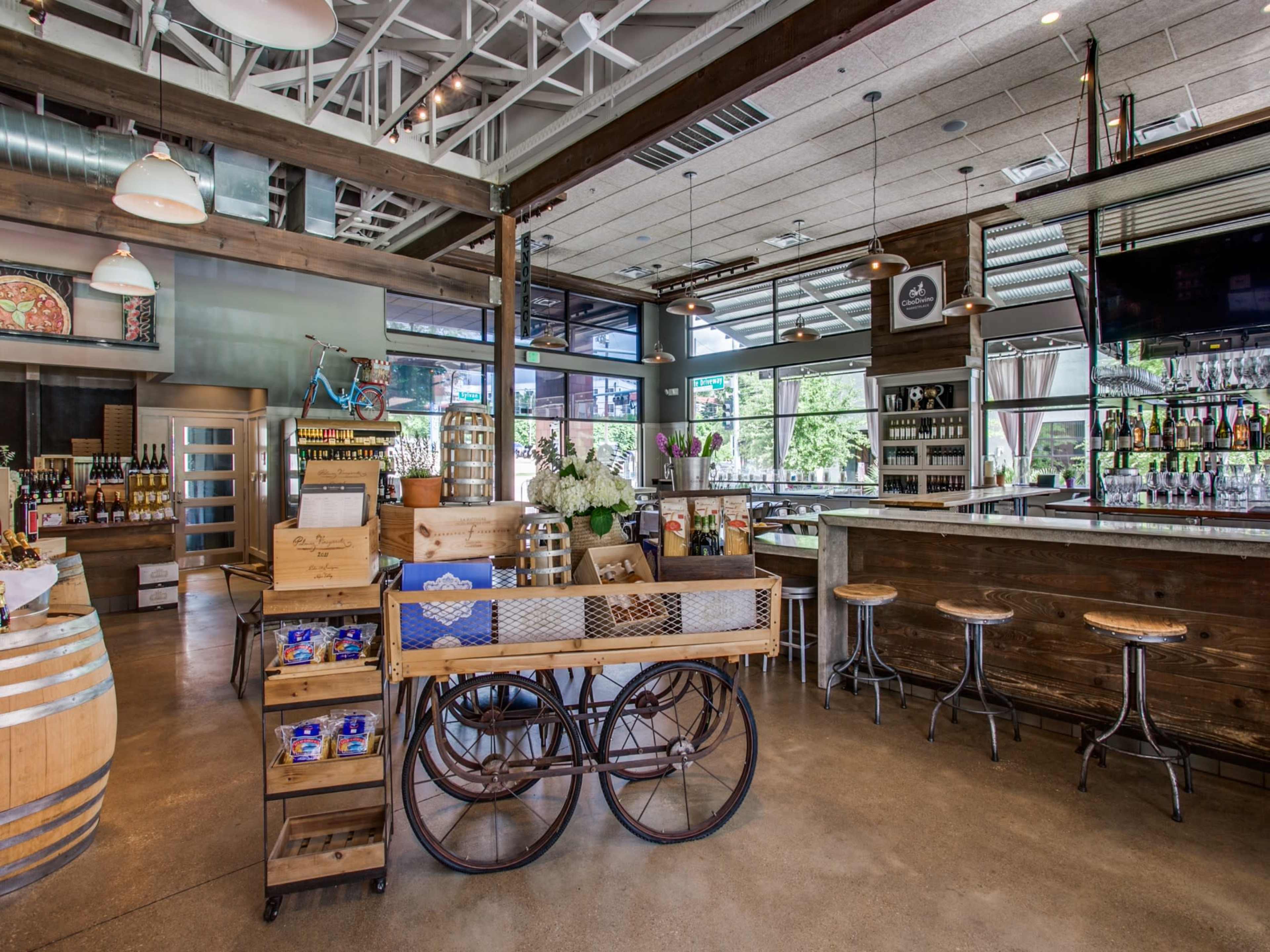 The interior of a modern bar and market featuring wooden accents, a bike displayed on the wall, and bar stools arranged around a counter.