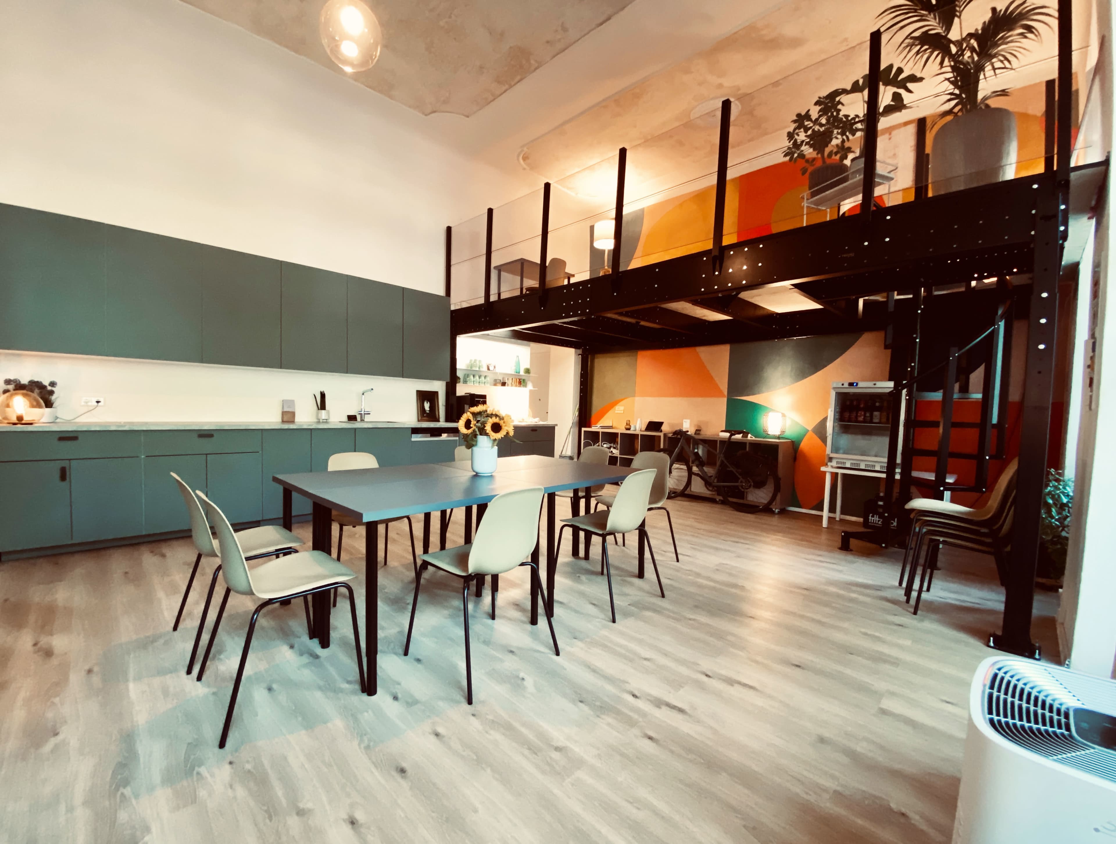 A modern open-plan kitchen and dining area with a large table and chairs, leading to a lofted space above.