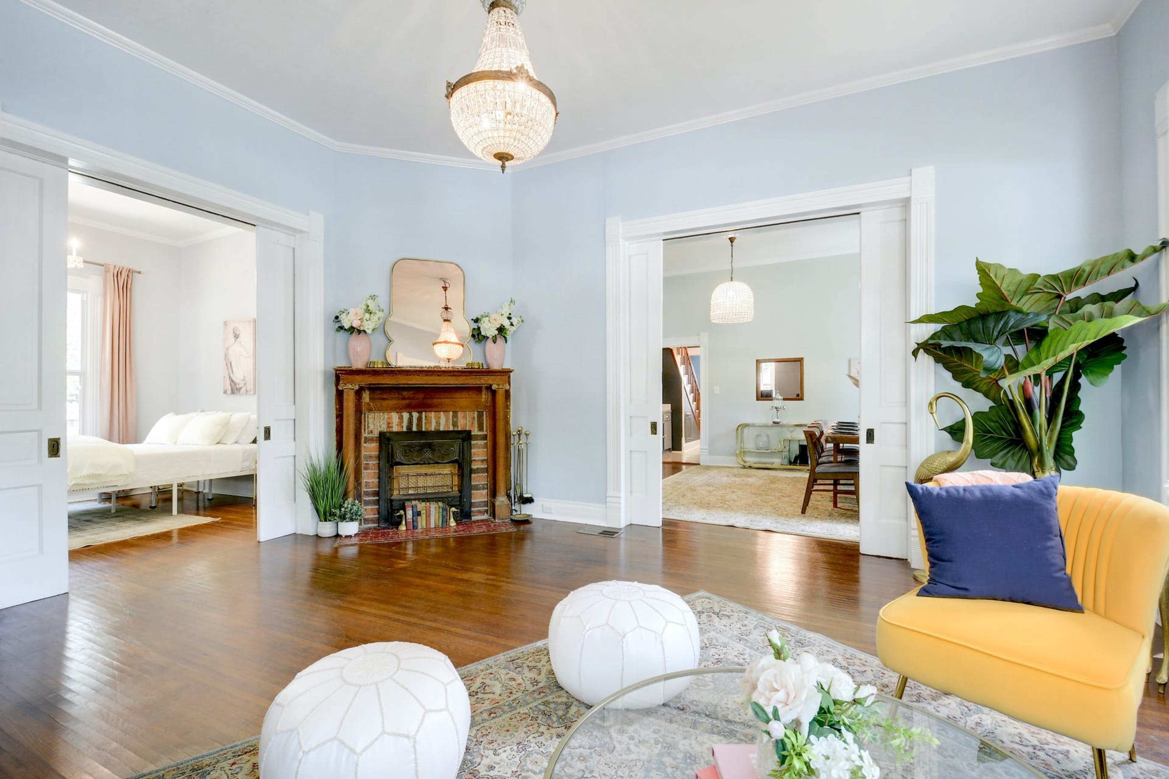 A bright living room features hardwood floors, a vintage fireplace, and two doorways leading to adjacent rooms.