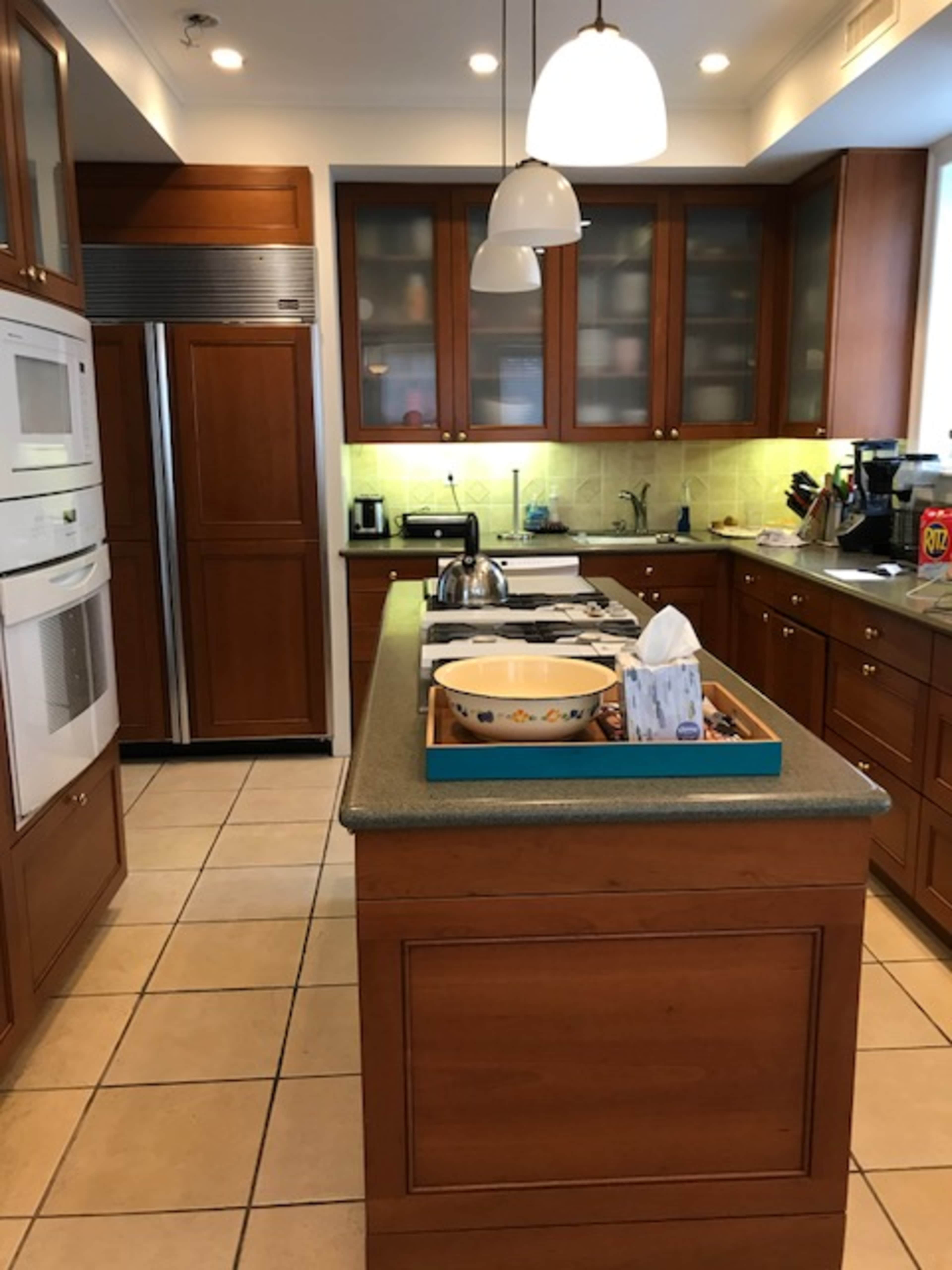 A modern kitchen features wooden cabinets, a central island with a blue tray, and stainless steel appliances.