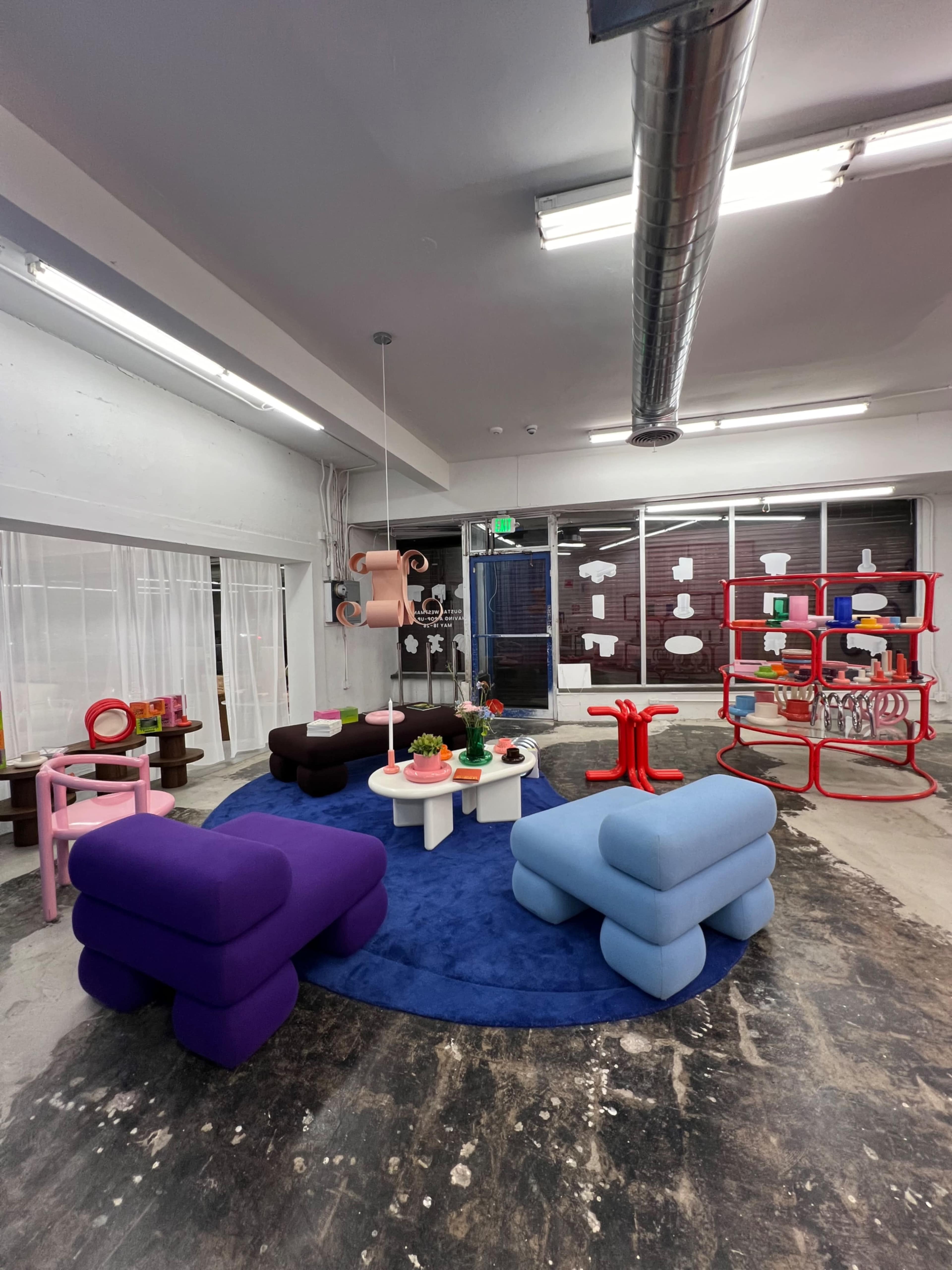 A modern interior space featuring colorful furniture items, including sofas and tables, arranged on a circular rug.