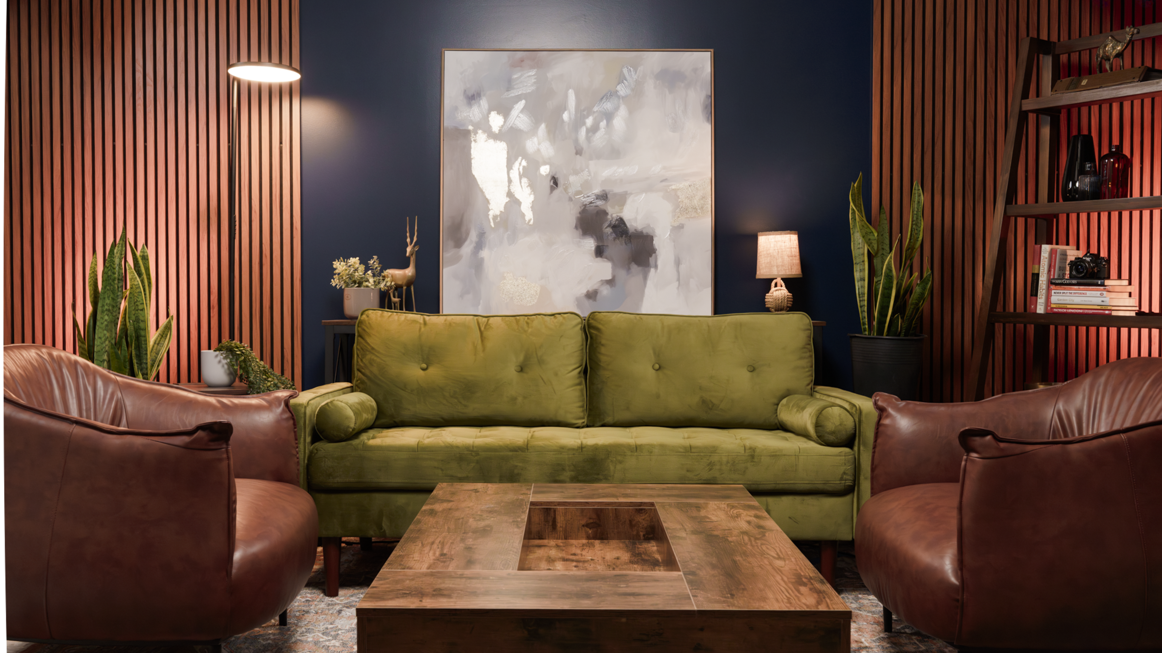 A green sofa is positioned between two brown armchairs in a room with wooden paneling and a large abstract painting on the wall.