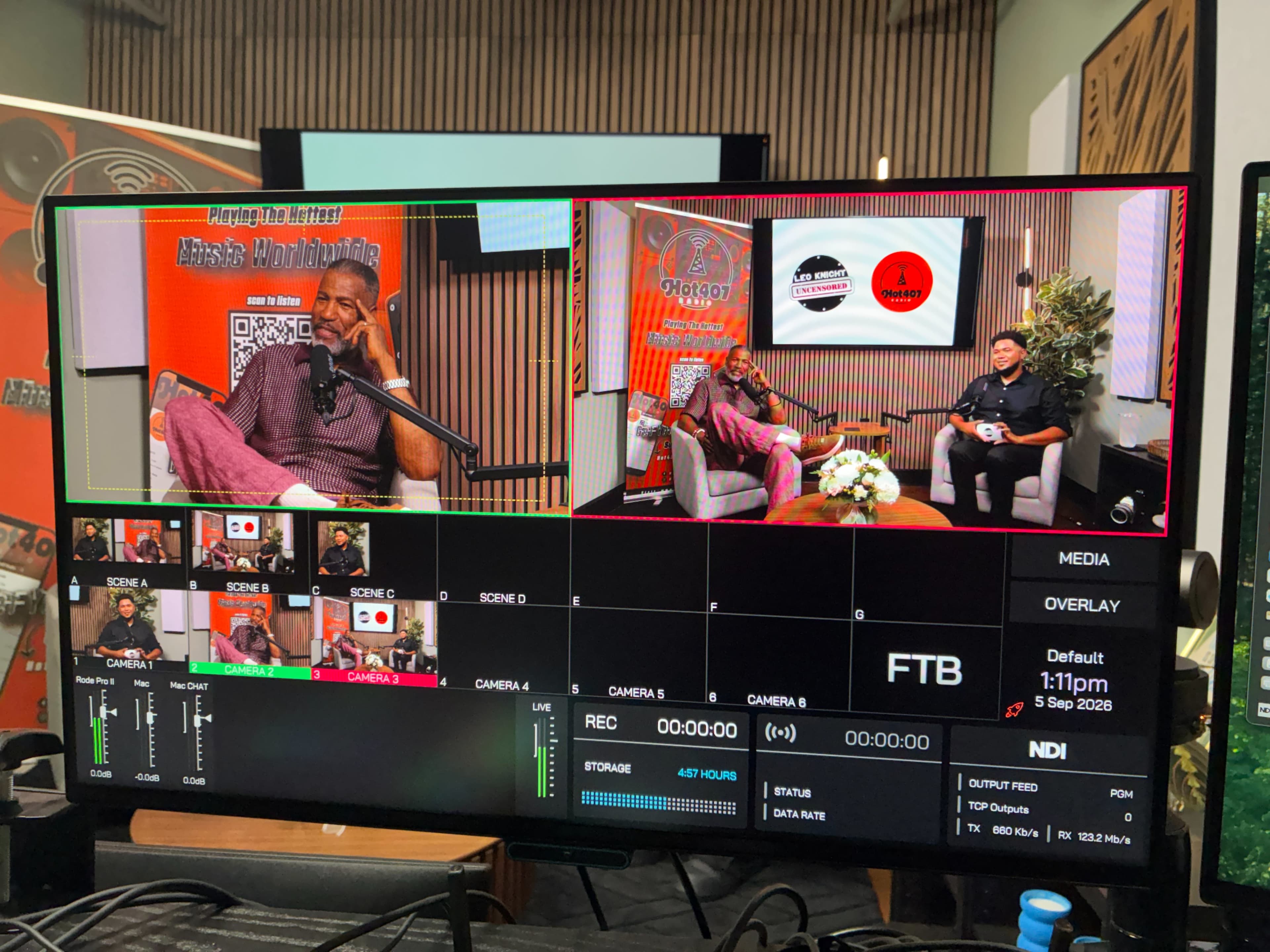 The image shows a control board displaying various camera angles and scenes for a recorded television or podcast setup with two hosts seated and engaged in a discussion.