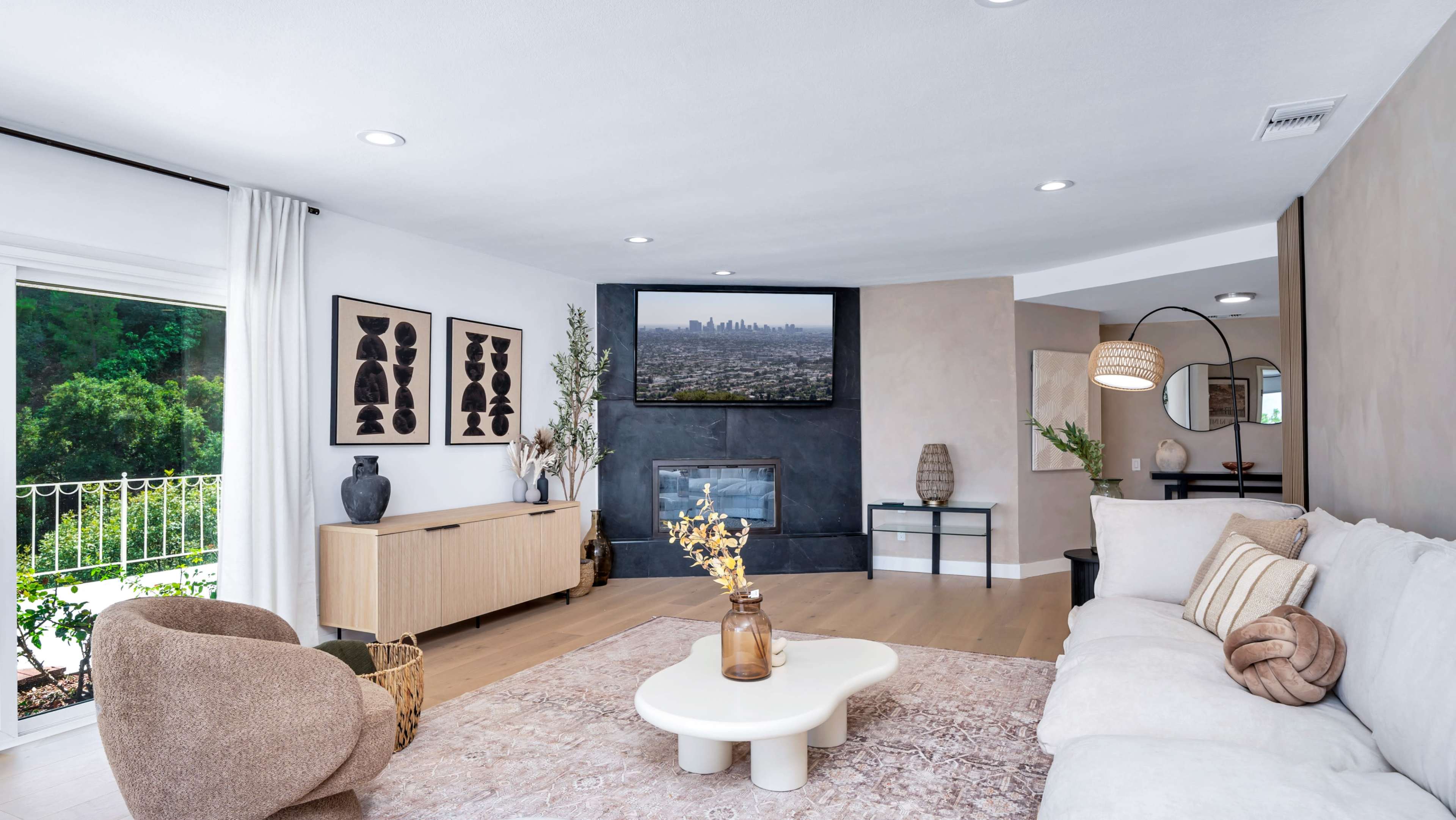 The living room features a modern design with a neutral color palette, a comfortable sofa, and a wall-mounted television above a fireplace.