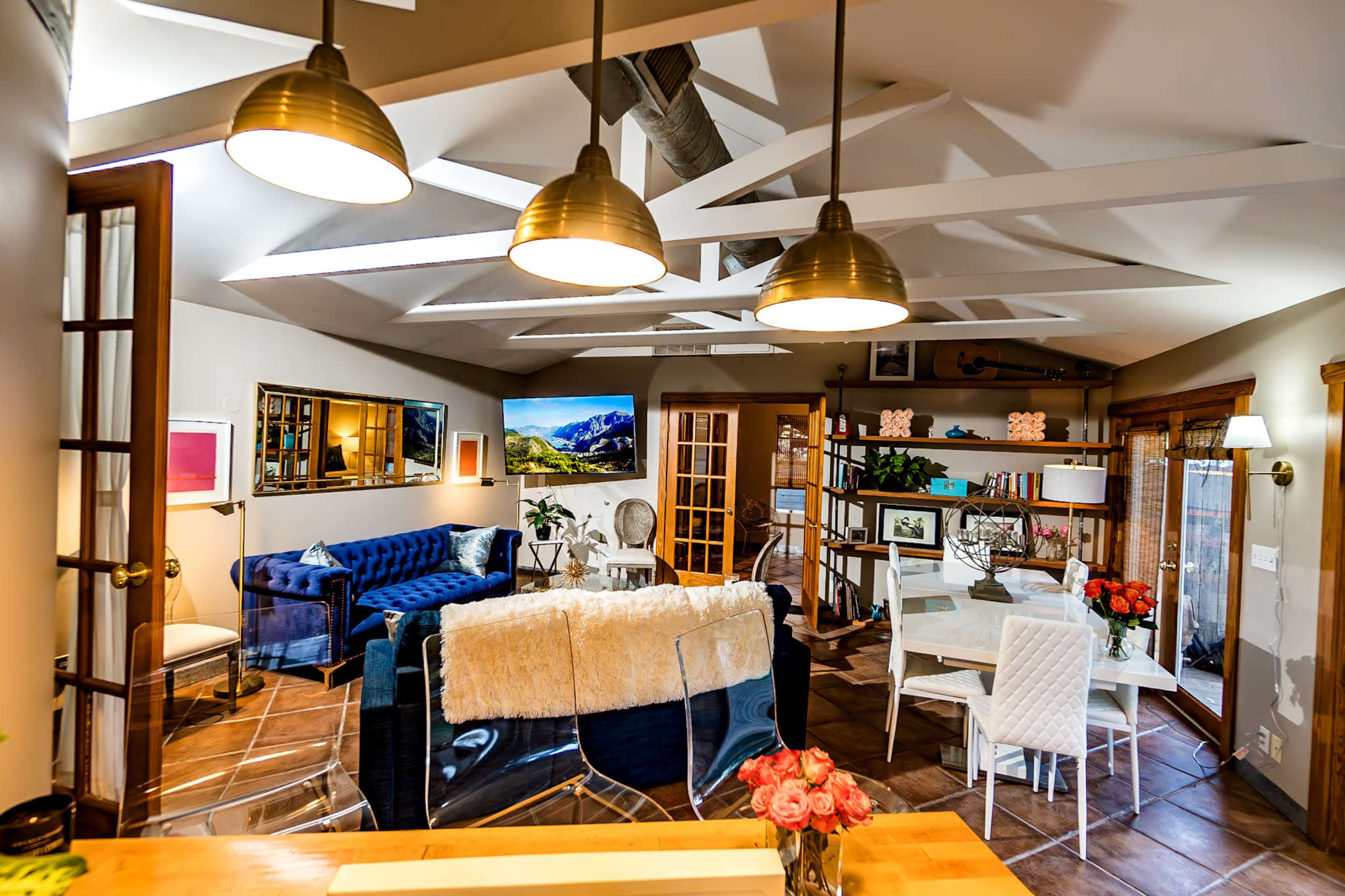 A well-lit, open-concept living and dining area features modern furniture, including a blue sofa, a glass dining table, and a stylish decor arrangement.