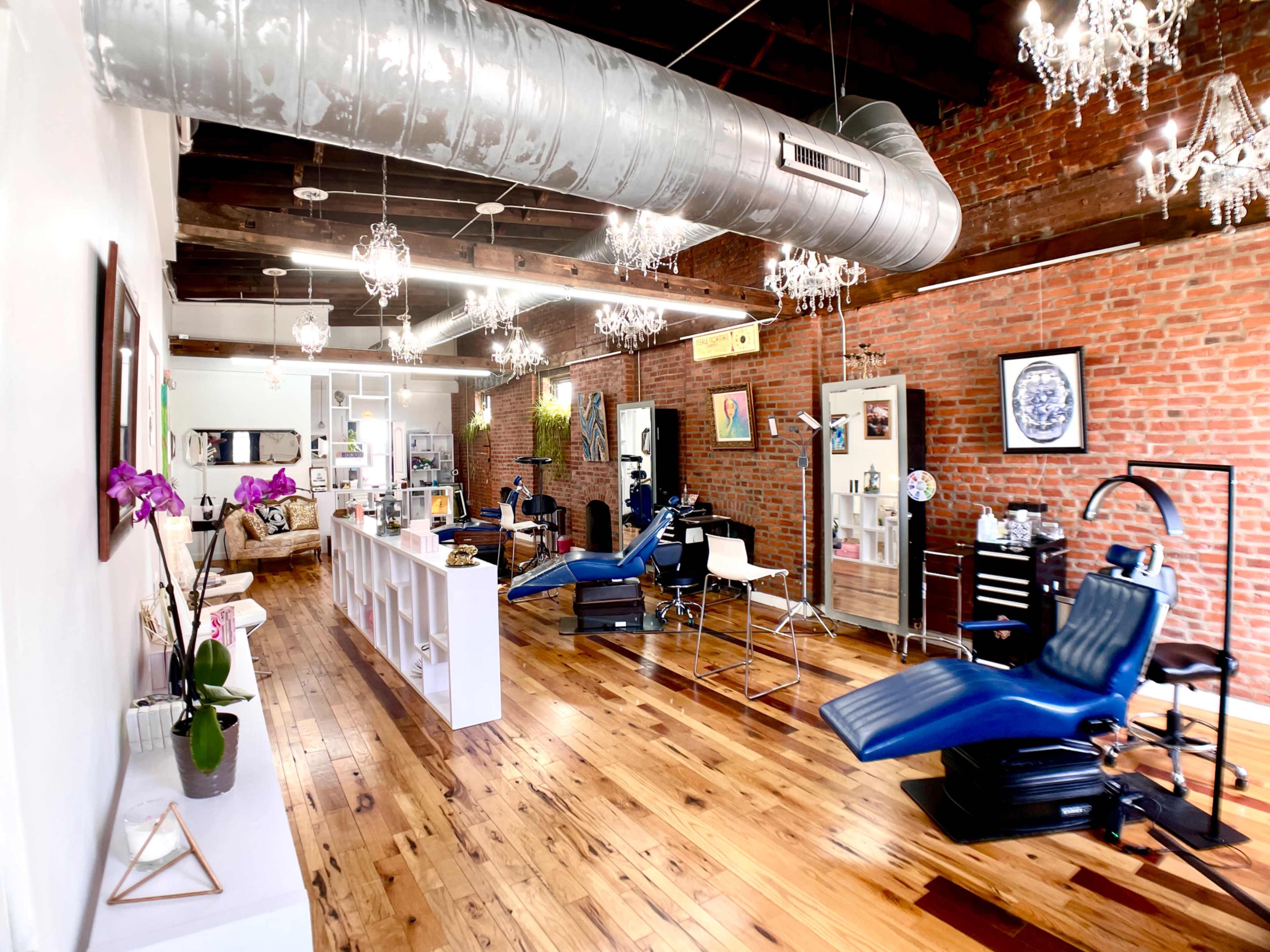 A tattoo studio with brick walls, wooden flooring, and modern equipment arranged in a spacious layout.