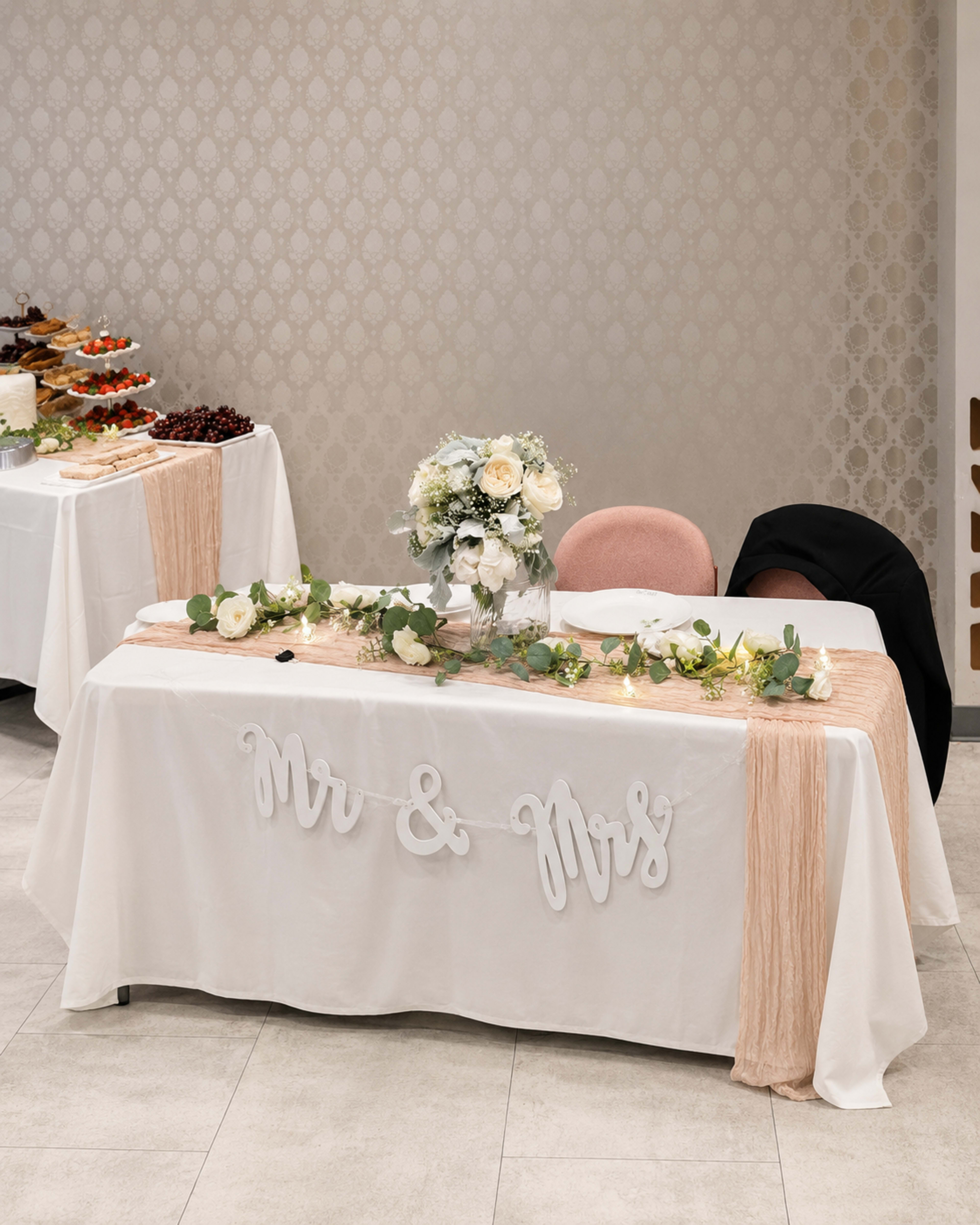 A decorated wedding reception table with a floral centerpiece and the words "Mr & Mrs" displayed prominently.
