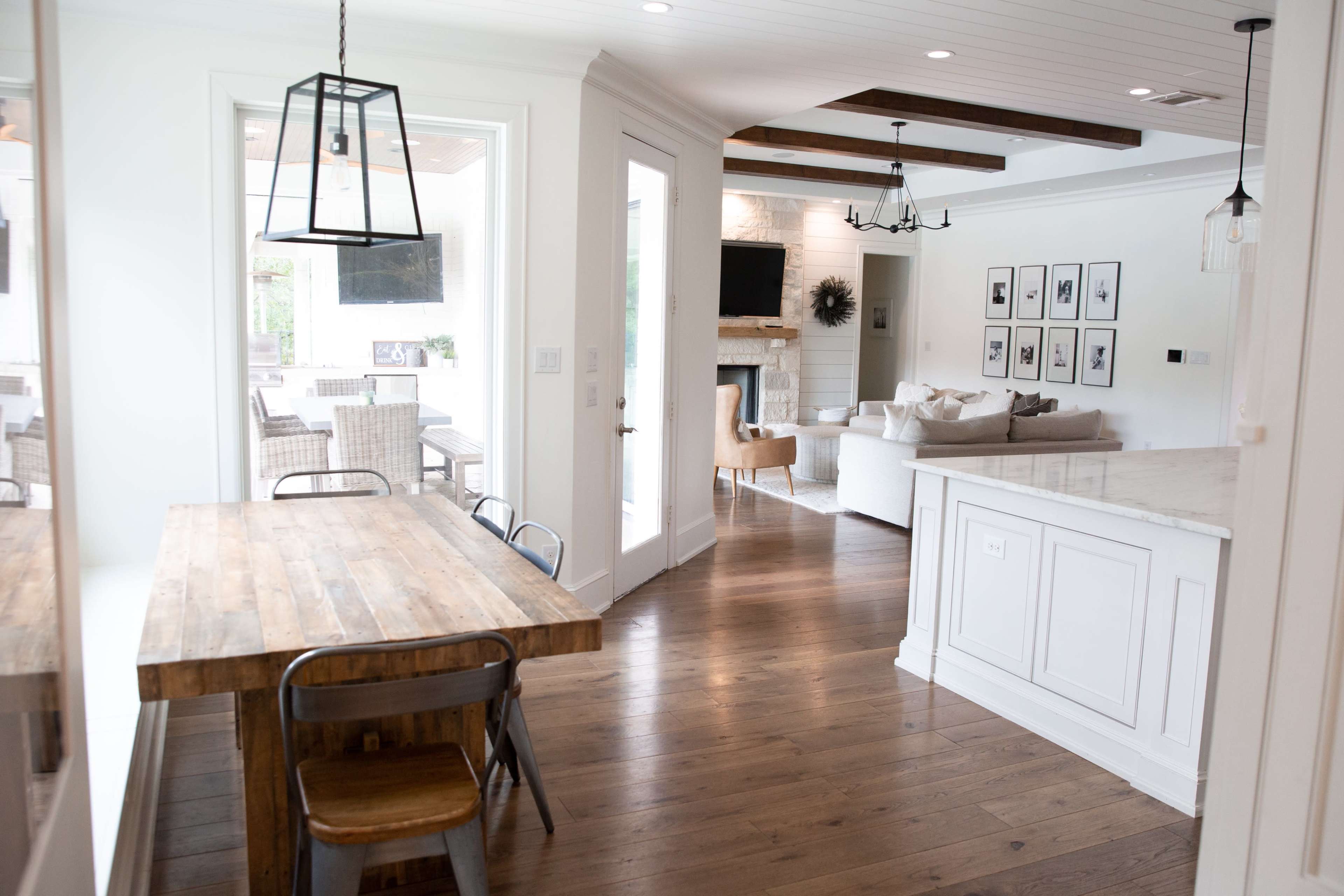 A bright, open-concept living space featuring a dining table, a kitchen island, and a cozy seating area with a fireplace.