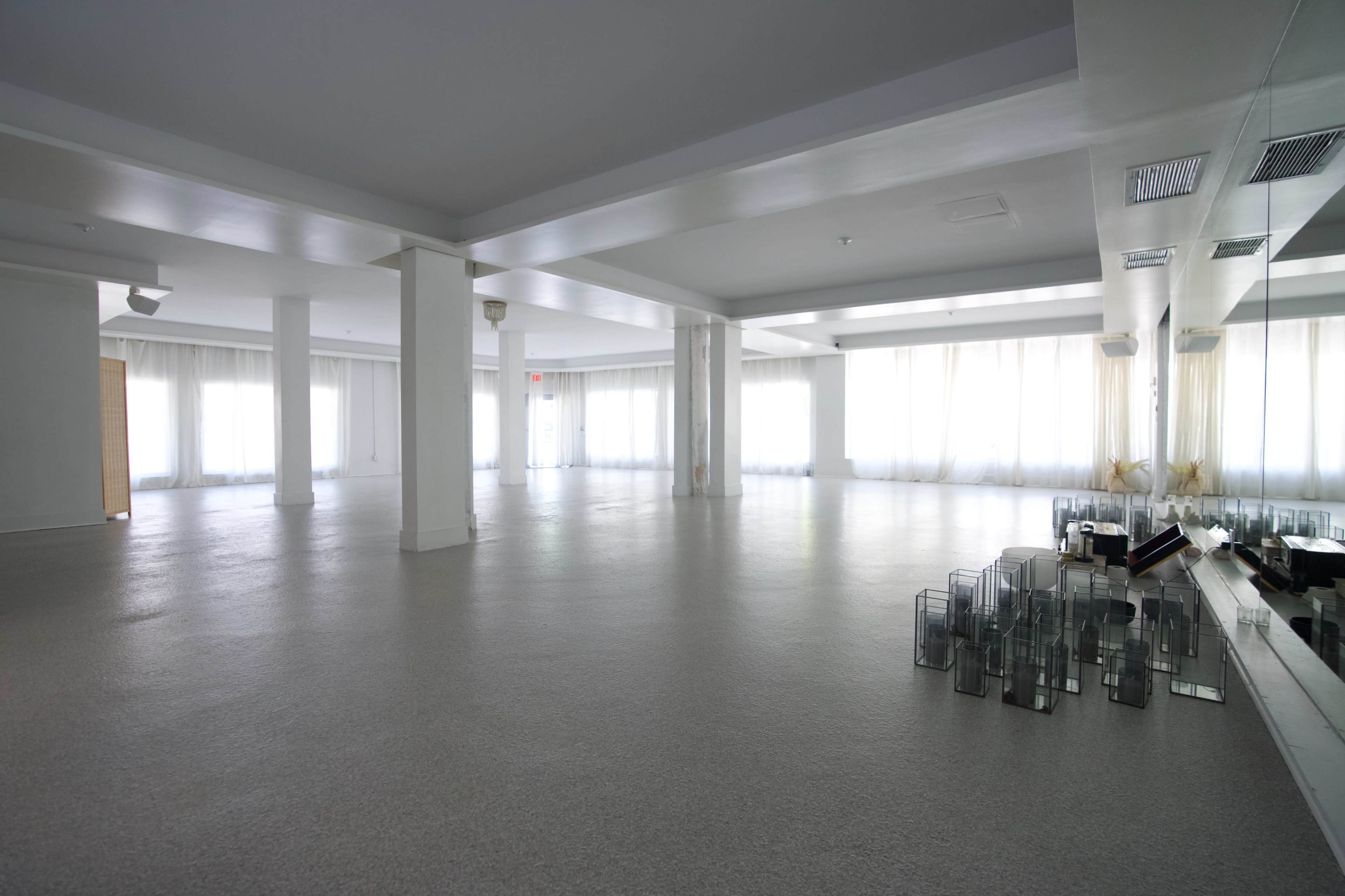 The image shows a spacious, empty room with large windows and a smooth, light-colored floor.