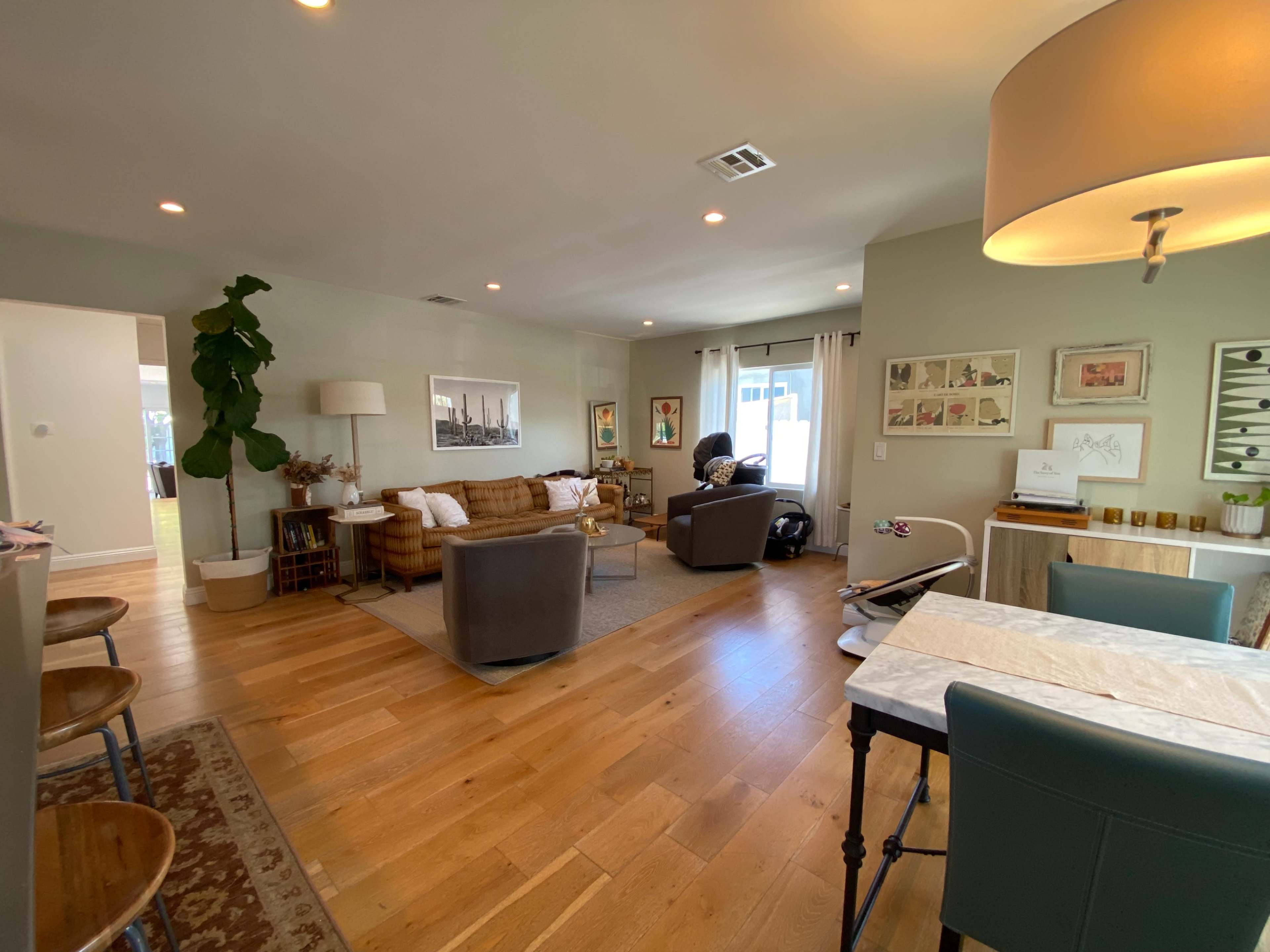 A spacious living area featuring a mix of seating, artwork on the walls, and a dining table with chairs.