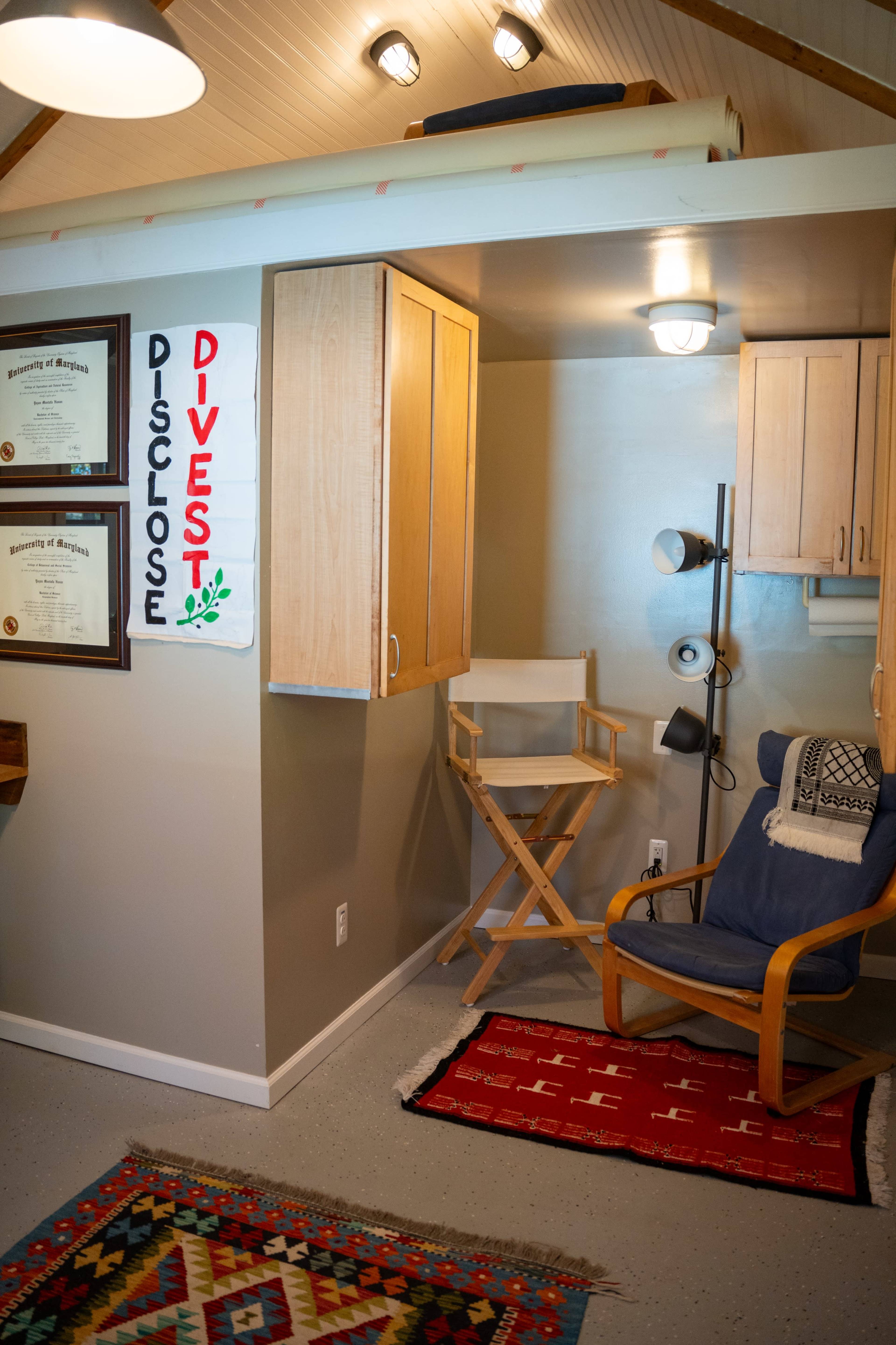 The image shows a well-organized office space featuring a chair, a small desk with storage cabinets, and framed certificates on the wall.