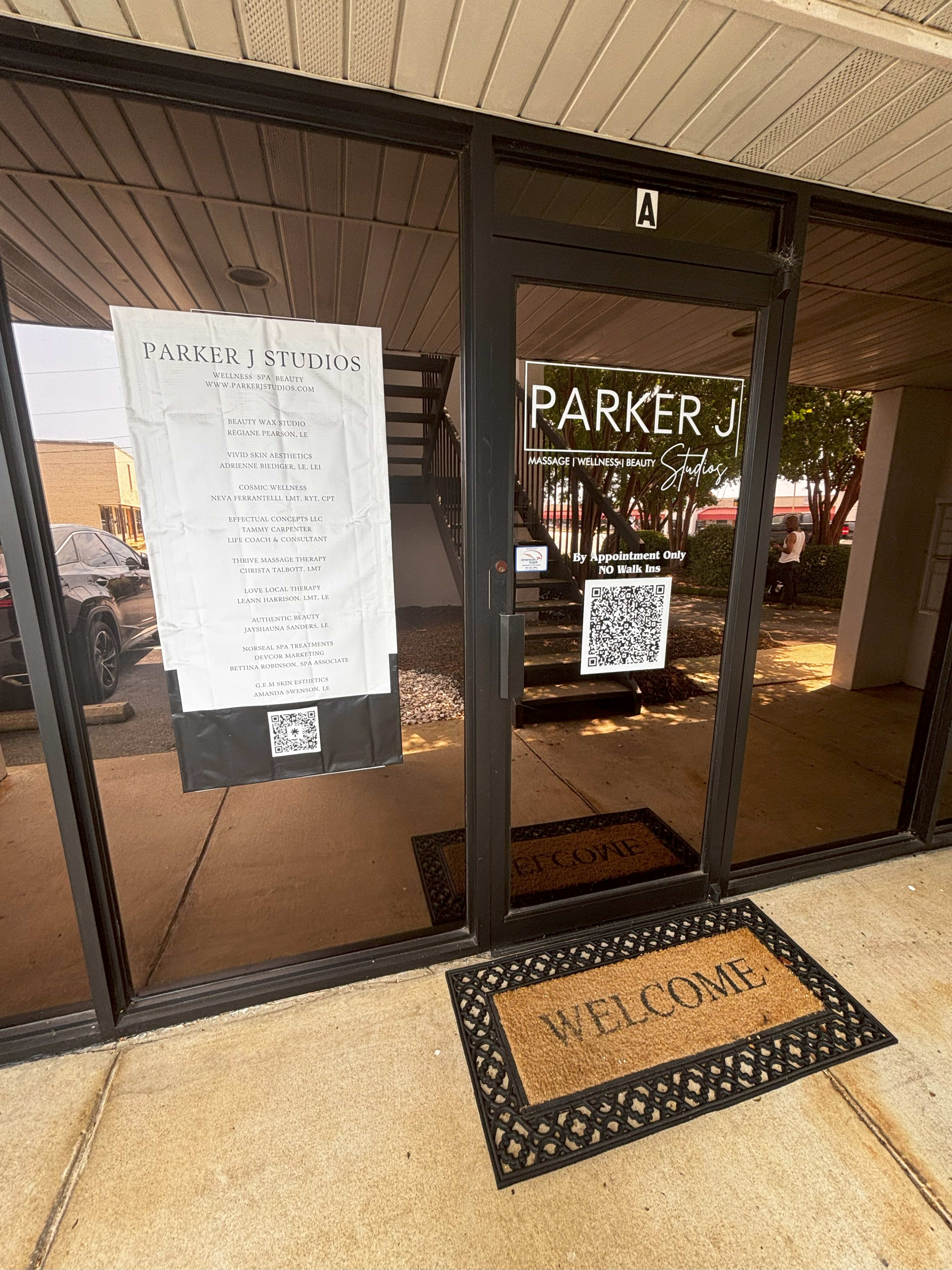 The entrance to Parker J Studios features glass doors with a welcoming mat and a large sign outlining services.
