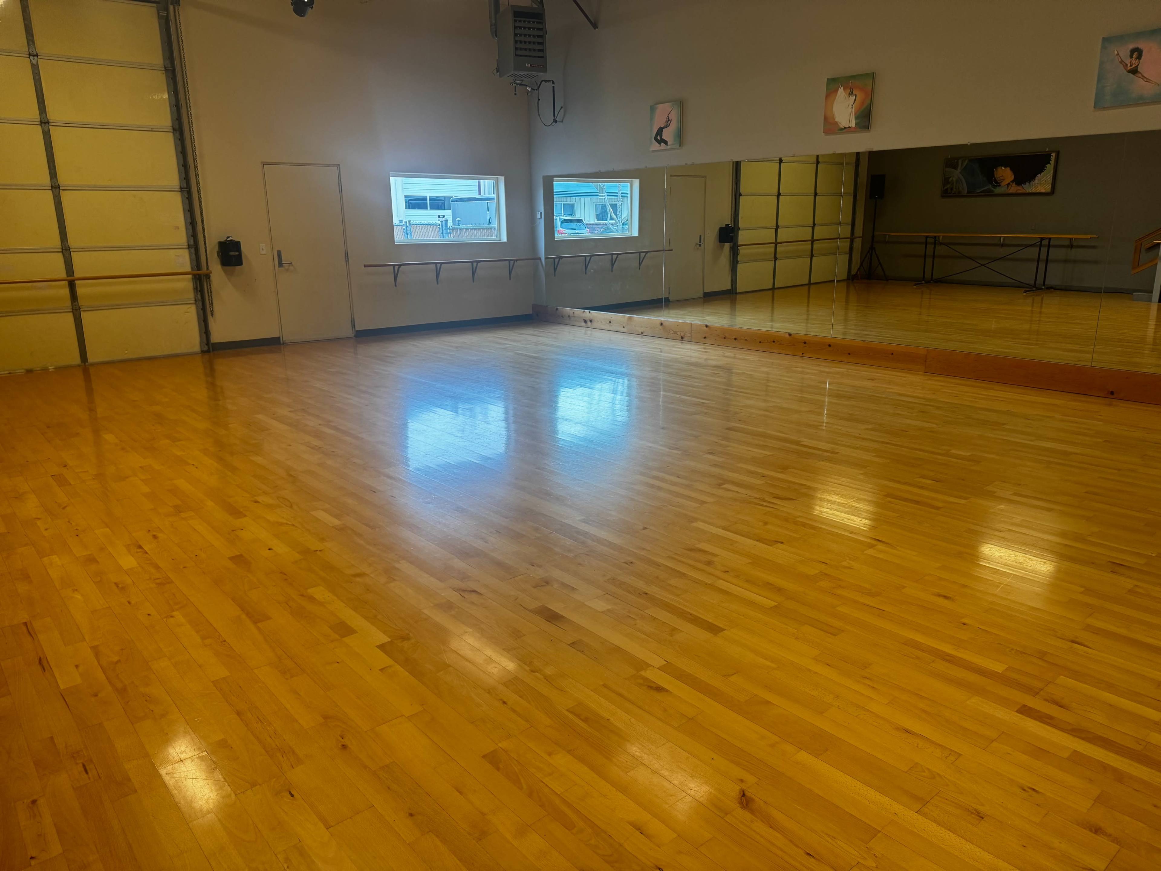 The image shows a spacious wooden dance studio with mirrors, large windows, and polished floorboards.