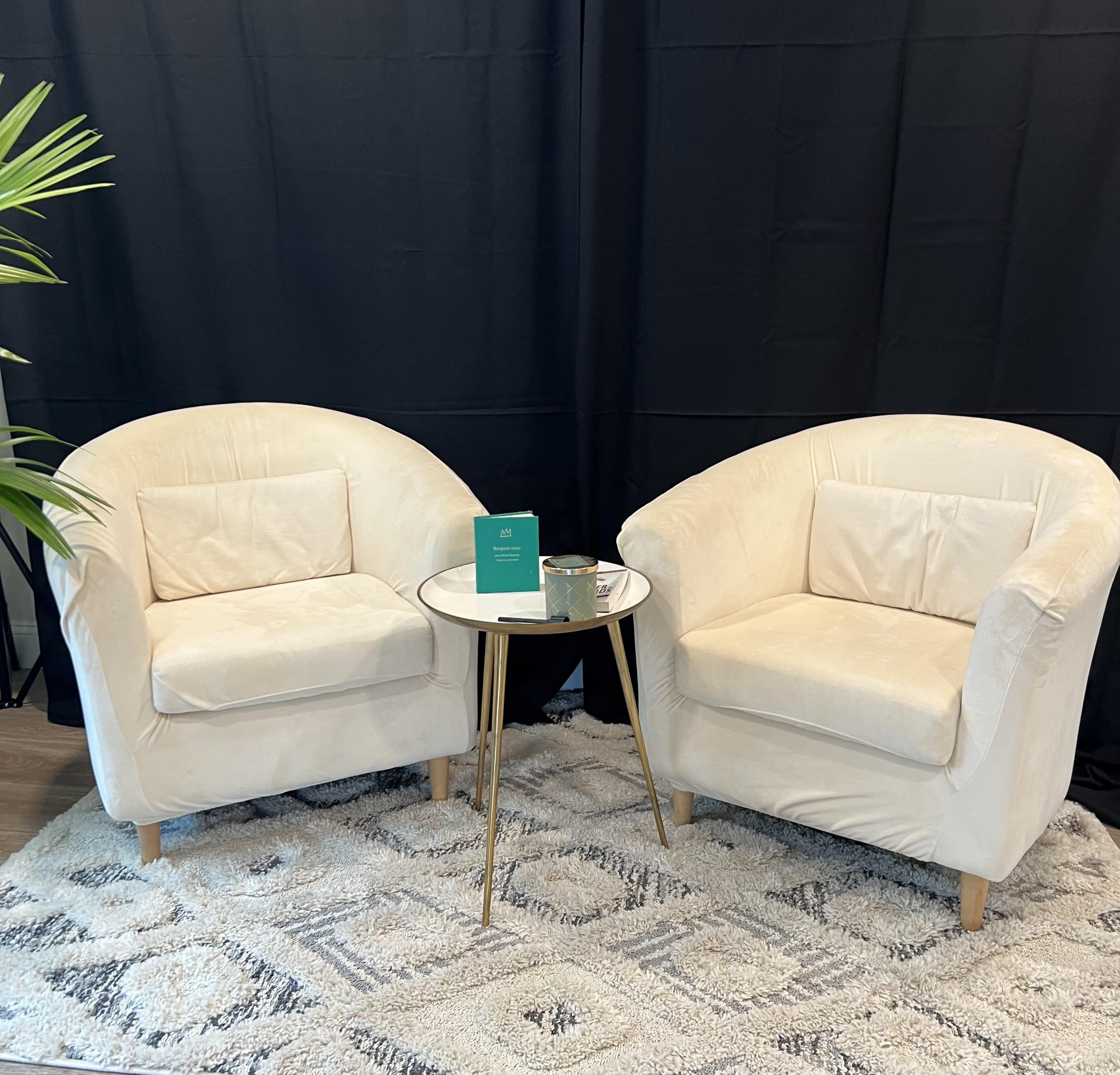 Two cream-colored chairs with round backs are positioned across from each other, accompanied by a small round table on a geometric-patterned rug.