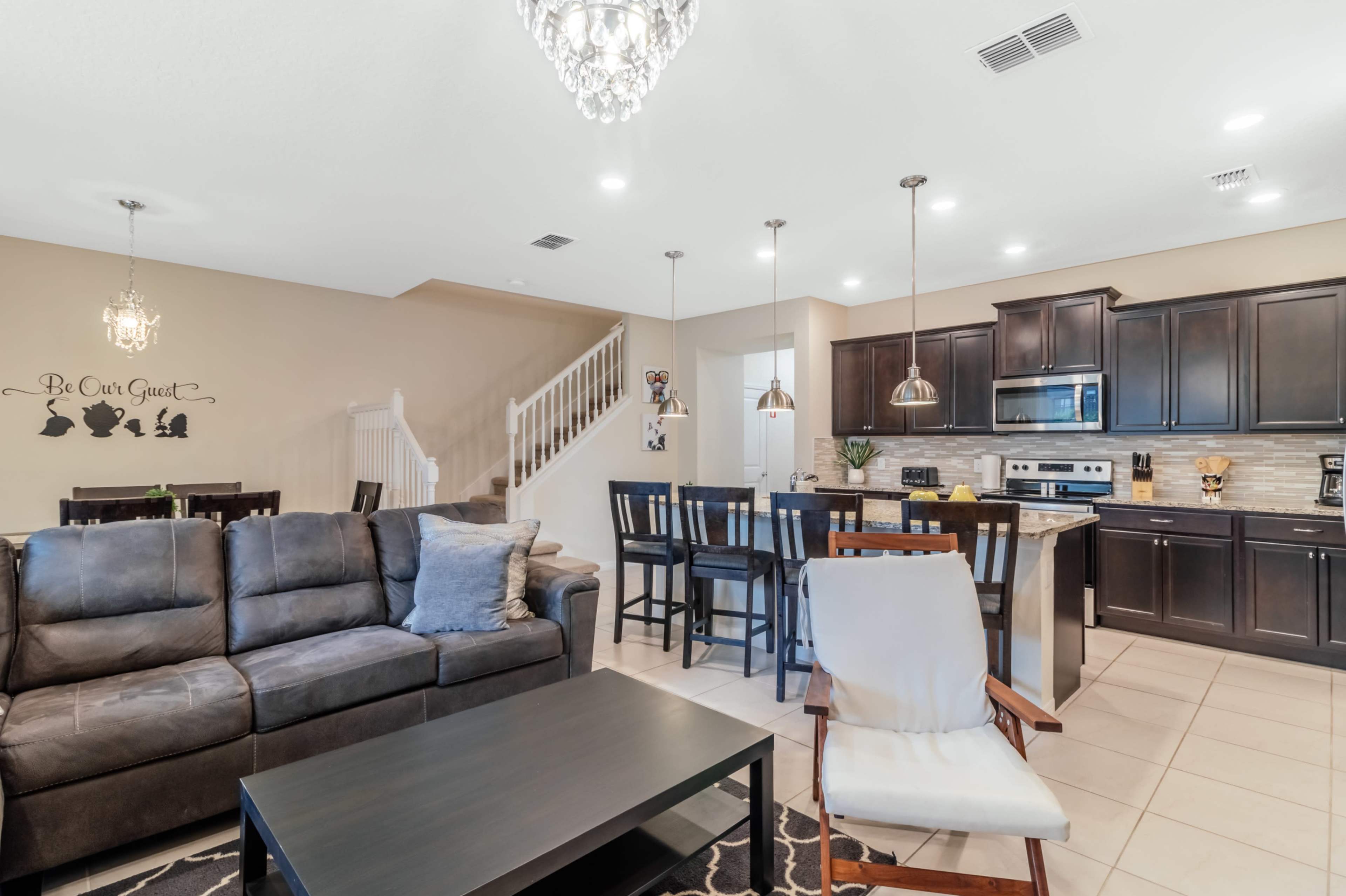 A modern living room and kitchen area featuring dark wood cabinets, a dining table, and a comfortable sofa.