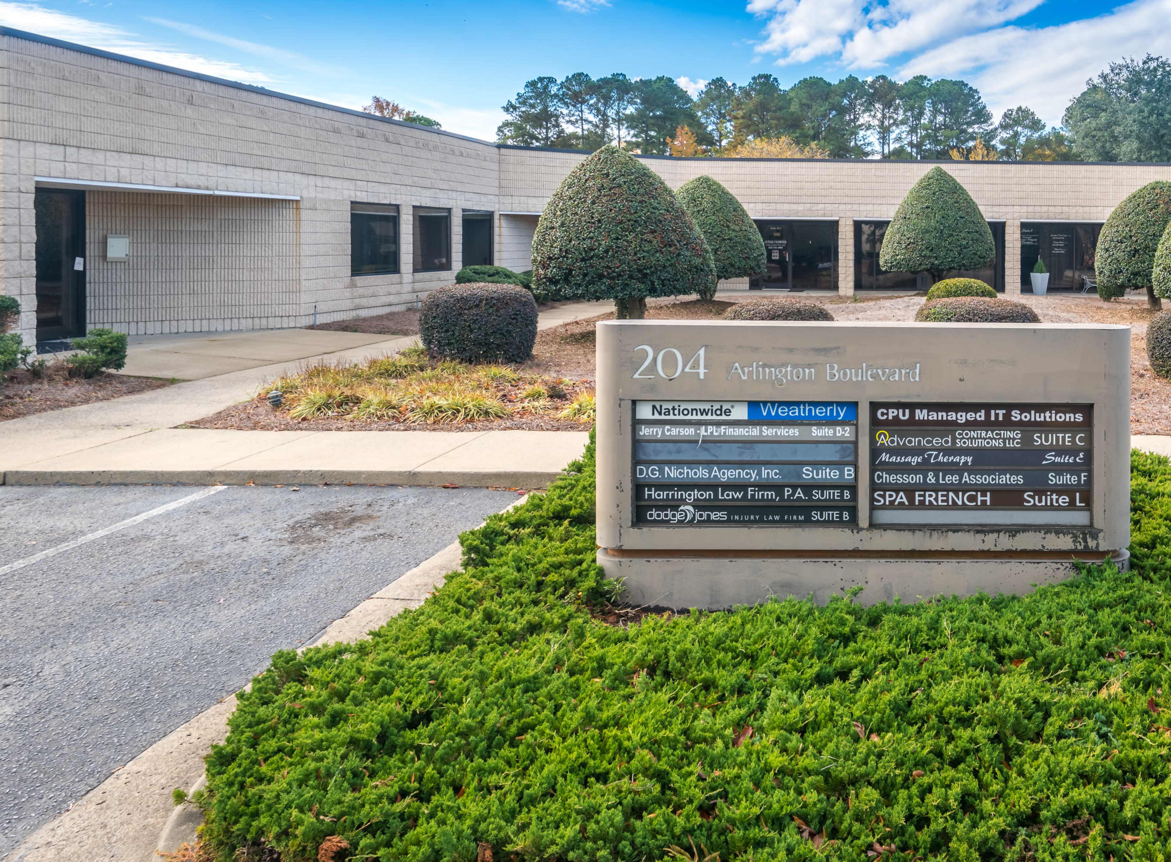 The image shows a commercial building on Arlington Boulevard with a landscaped entrance sign listing various businesses, including Nationwide Wealthery, CPU Managed IT Solutions, and Harrington Law Firm.