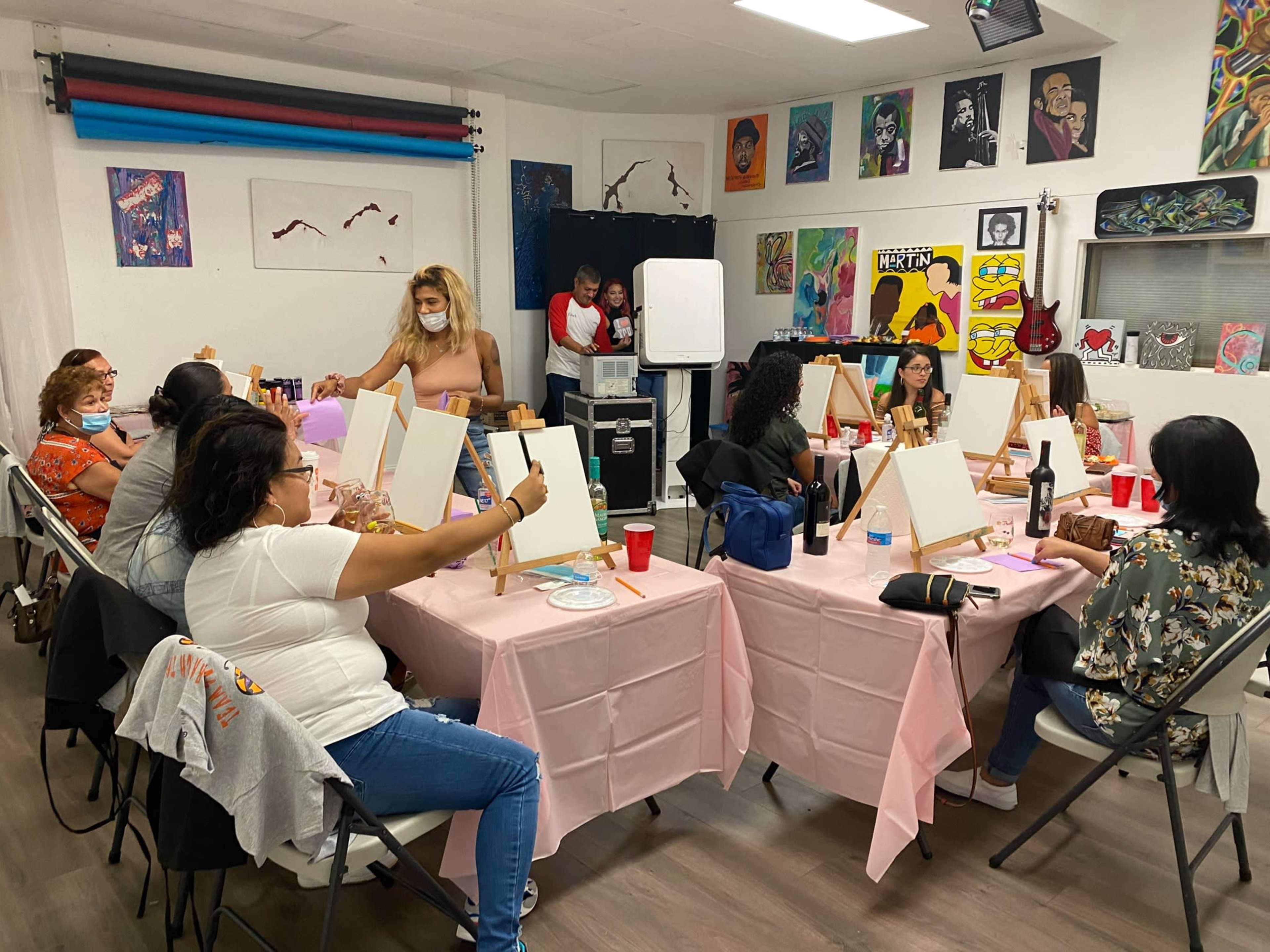 A group of people are participating in a painting class in a room decorated with various artworks.