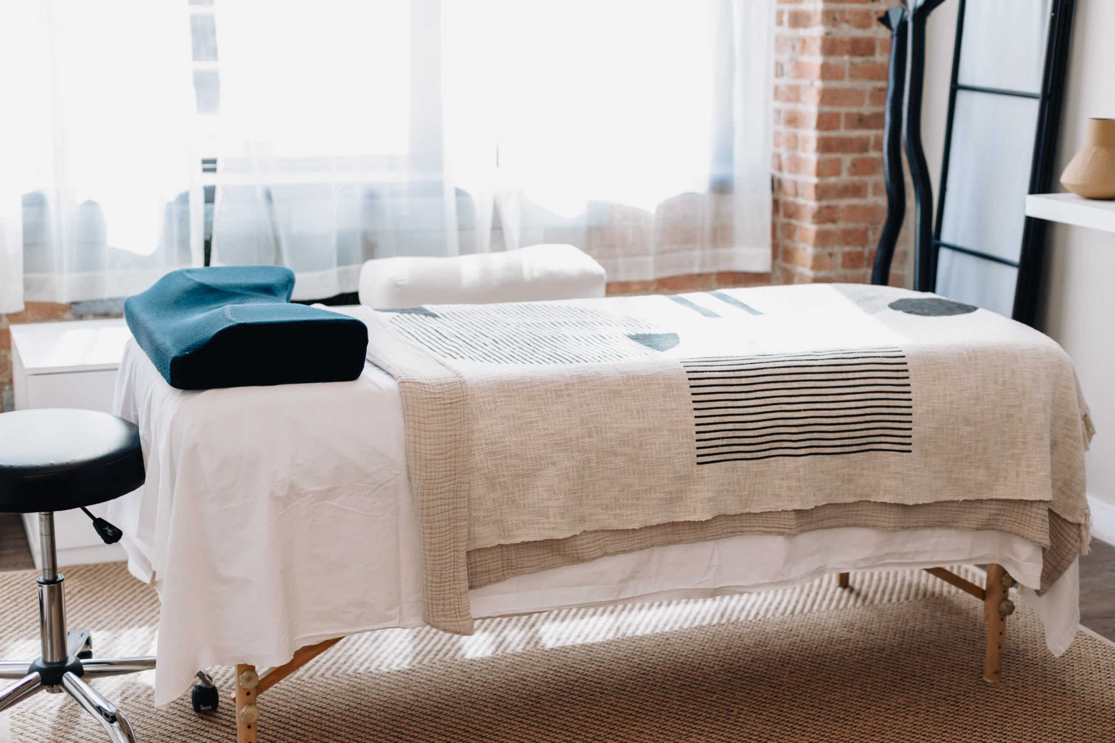 A massage table is set up in a well-lit room with natural light filtering through a window.