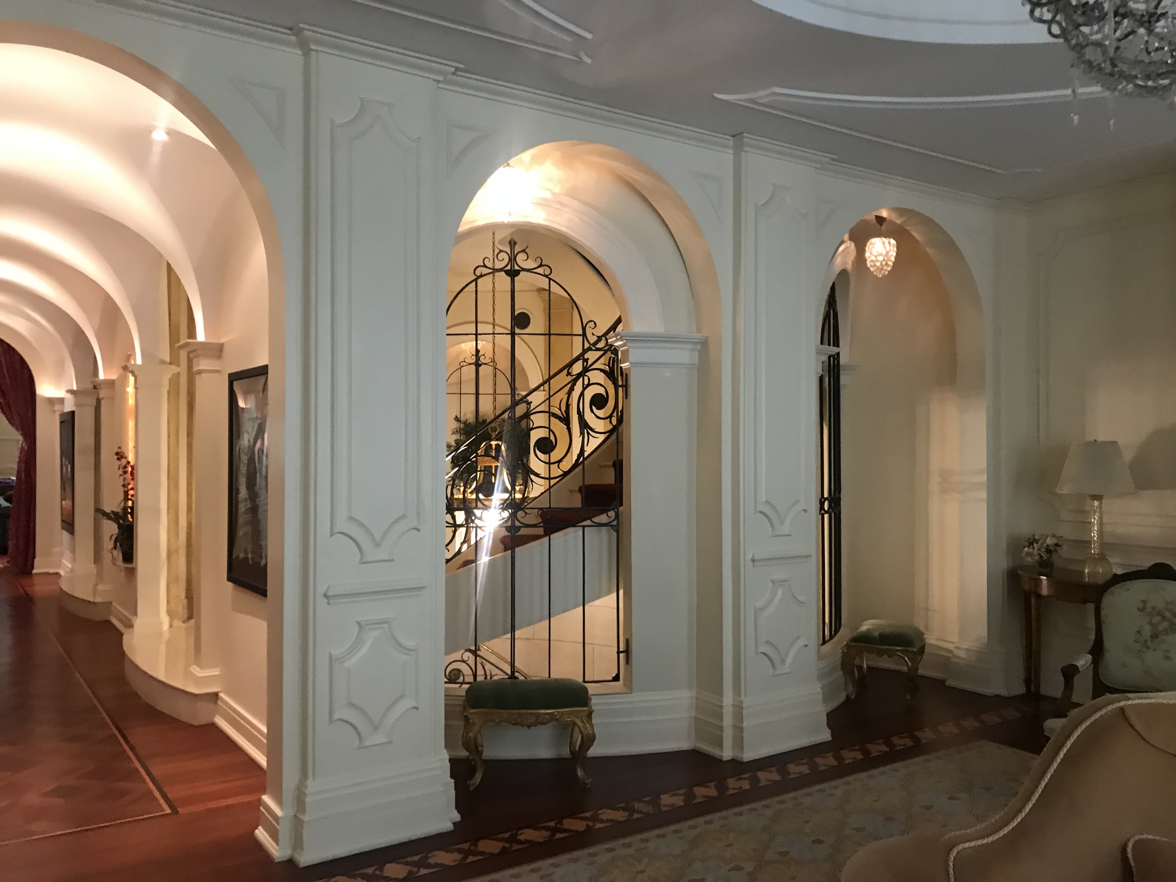 The image shows a softly lit hallway with arched doorways and a decorative staircase in the background.